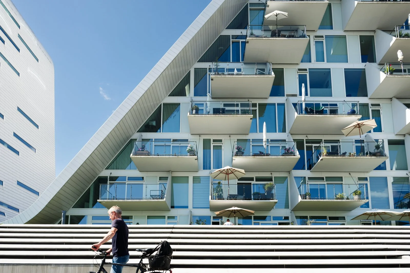 High-contrast facade and balcony section, showing the human scale and the geometric sharpness of the white shell.