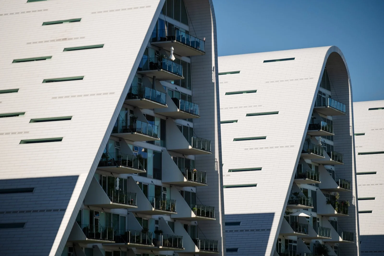 View from below The Wave, emphasizing the curved structural arch and the repetition of the layered balconies.