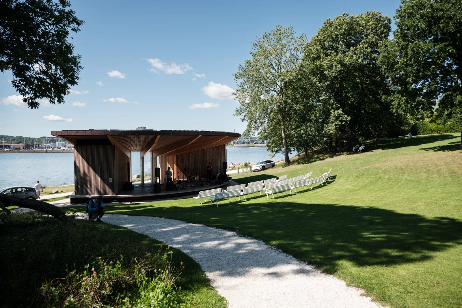 Skyttehushaven Park's organic pathway leading towards a simple, elegant wooden pavilion, blending nature with architectural sightlines.
