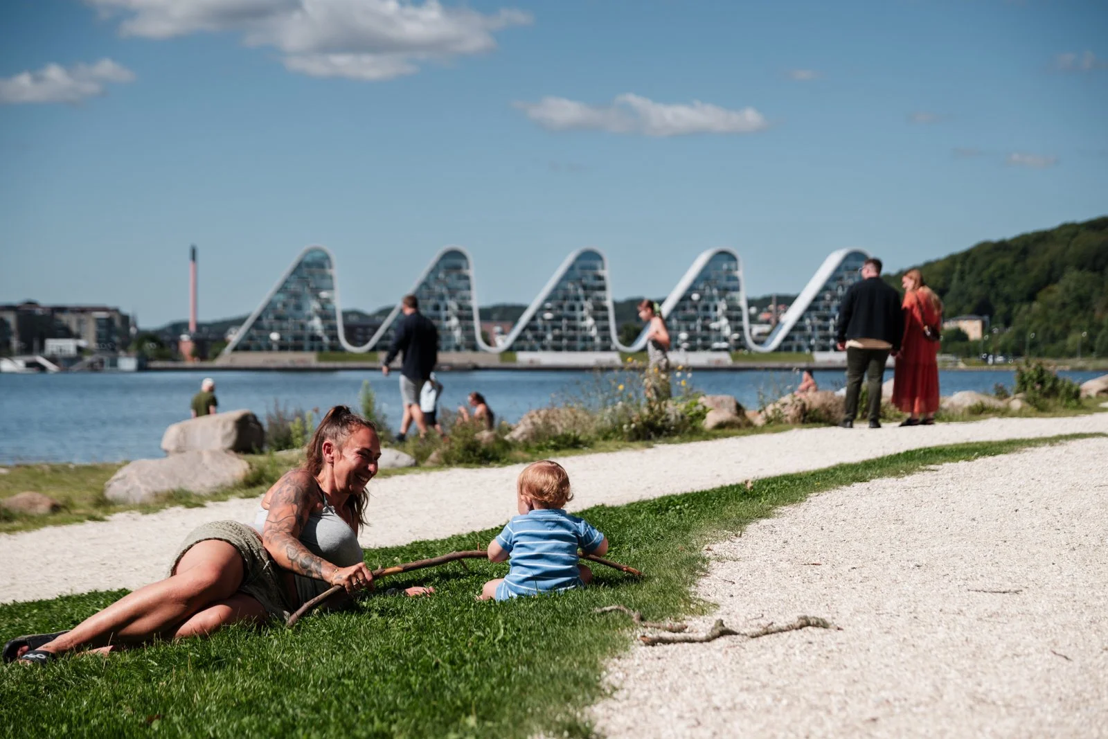 Nordic outdoor life in the park; resting on the grass, framing the distant architectural skyline across the water.