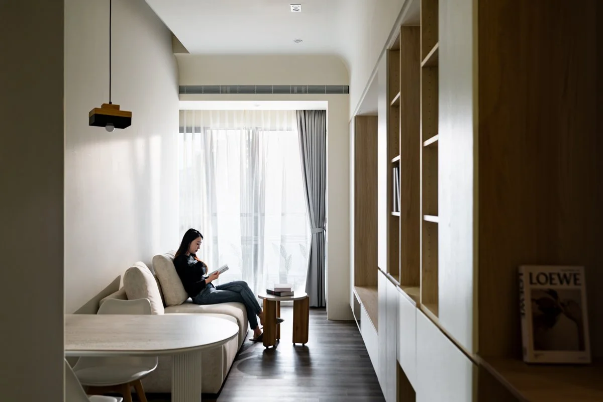 隨手拿起一本書，坐在日光掃落的窗邊，聽著溪水聲， 空間在此刻靜止，卻也在中流動著。 柔軟的光線與簡約的線條勾勒出生活的留白，讓人得以自在地安放思緒，也讓家的定義回歸純粹。