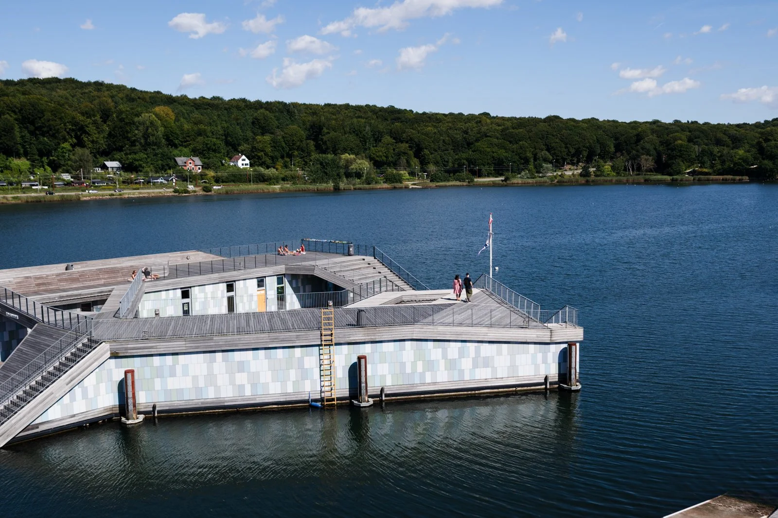 The Wave from the fjord, capturing the full scale of the complex and its relationship to the open water and natural backdrop.