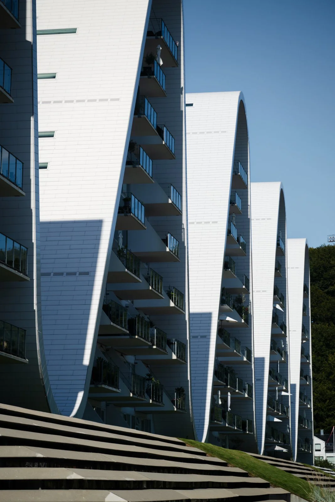 Close-up of The Wave's vertical facade highlighting the white tiled cladding and angled balconies against the sharp sky.