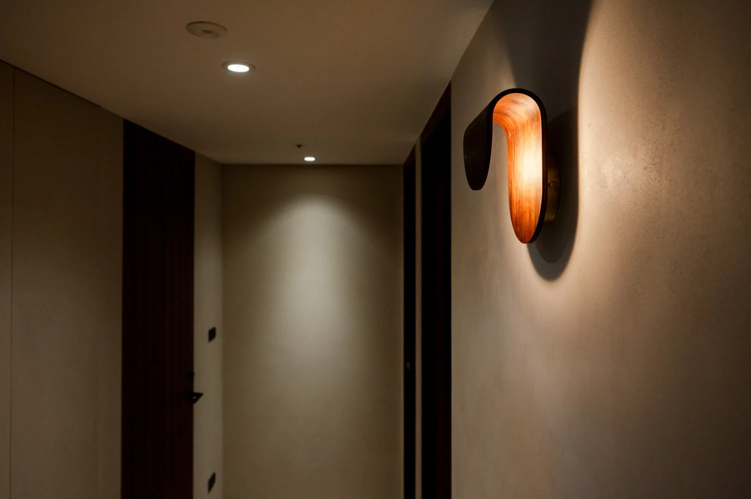 彎木工藝製作的設計感燈具特寫，光影變化展現出如鳥展翅般的優雅意象