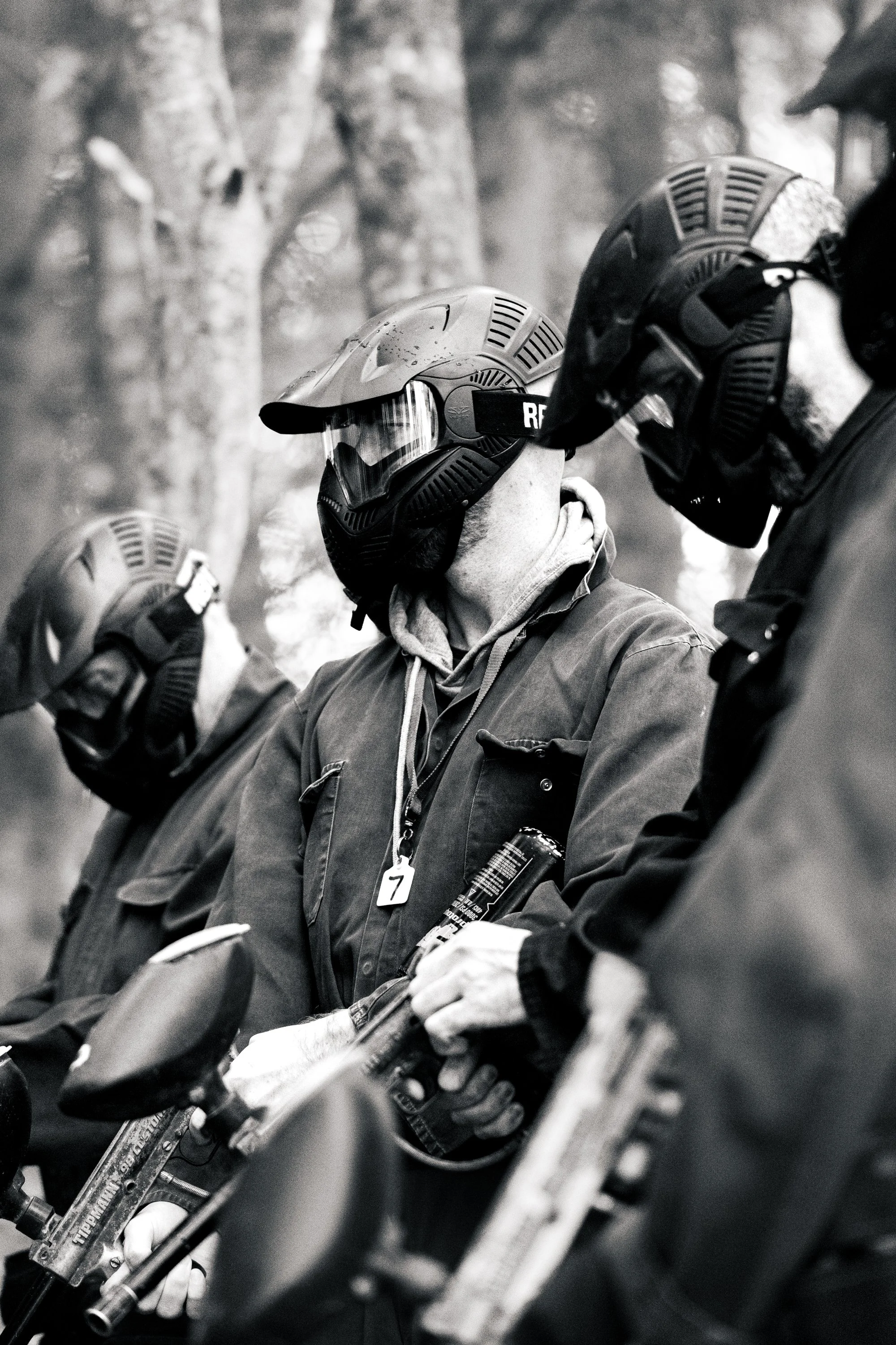 A group of firefighters wearing helmets and protective gear, standing with fire hoses, in a forested area.