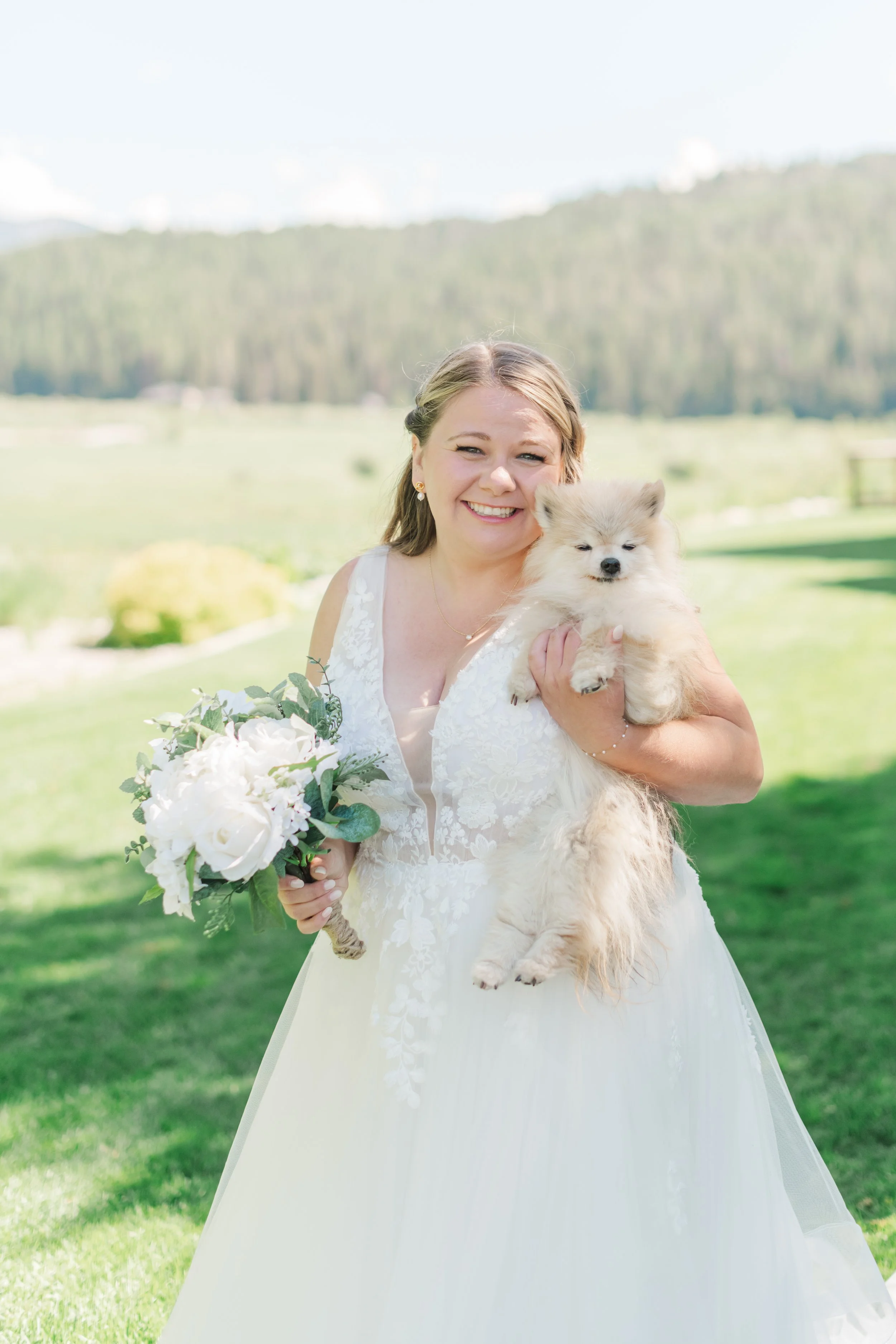  Bride holding her pomeranian dog and bouquet at the Star Valley Lodge and the mountains behind her 