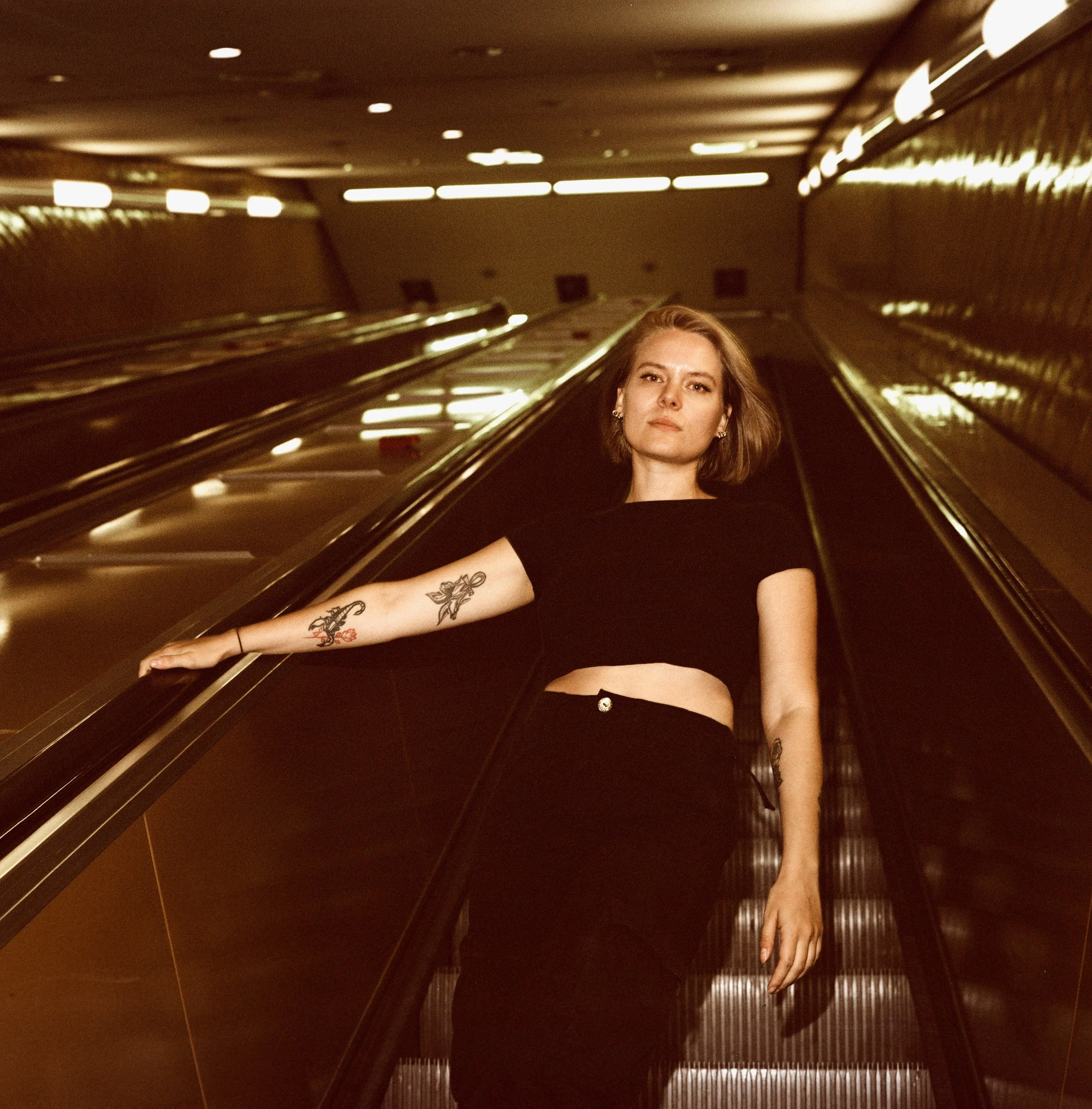 Urbanes und analoges Portrait einer jungen Frau auf der Rolltreppe der Hamburger U-Bahn.