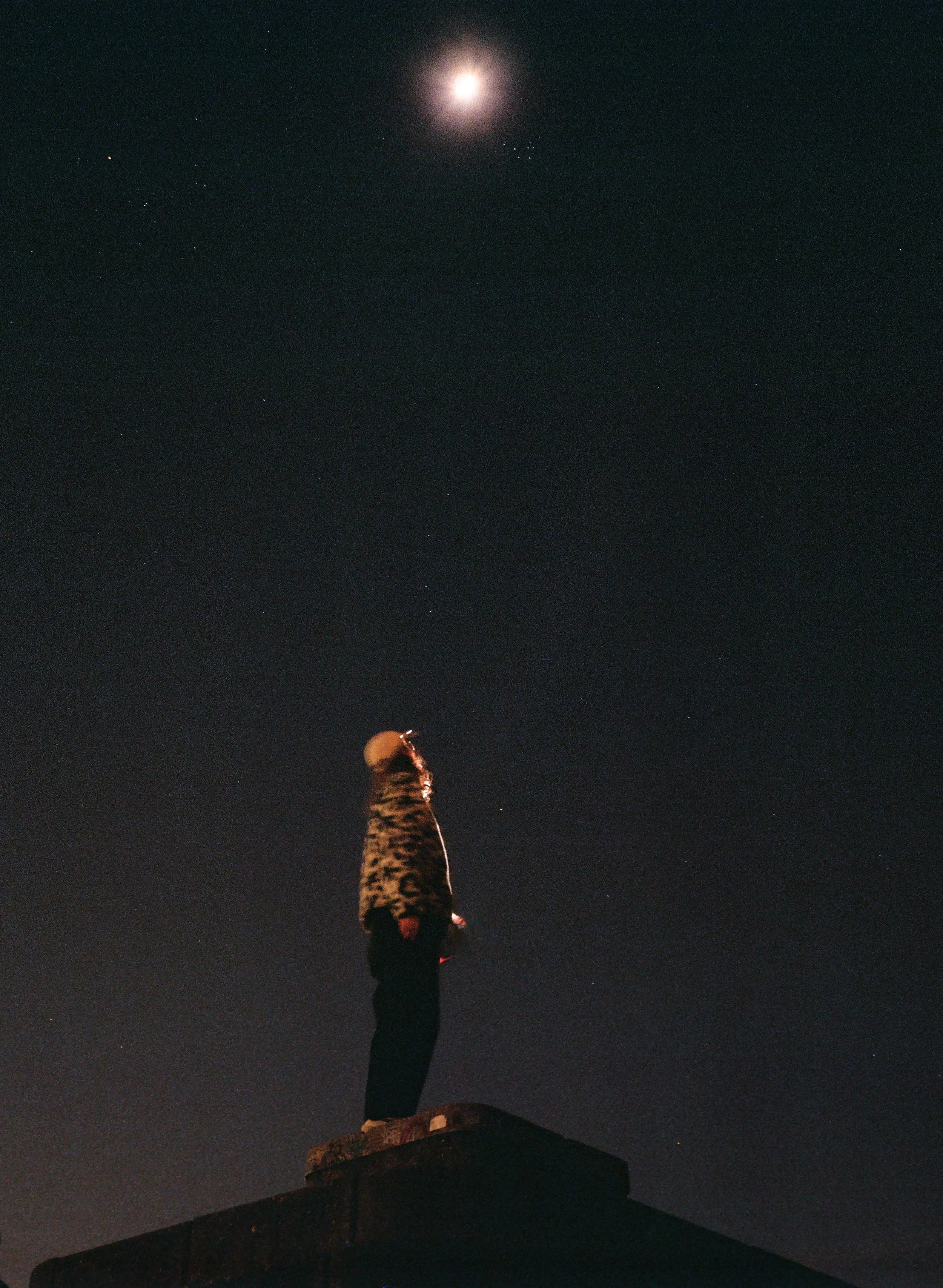Analoge Fotografie eines Mannes, der in einen magisch leuchtenden Sternenhimmel schaut.