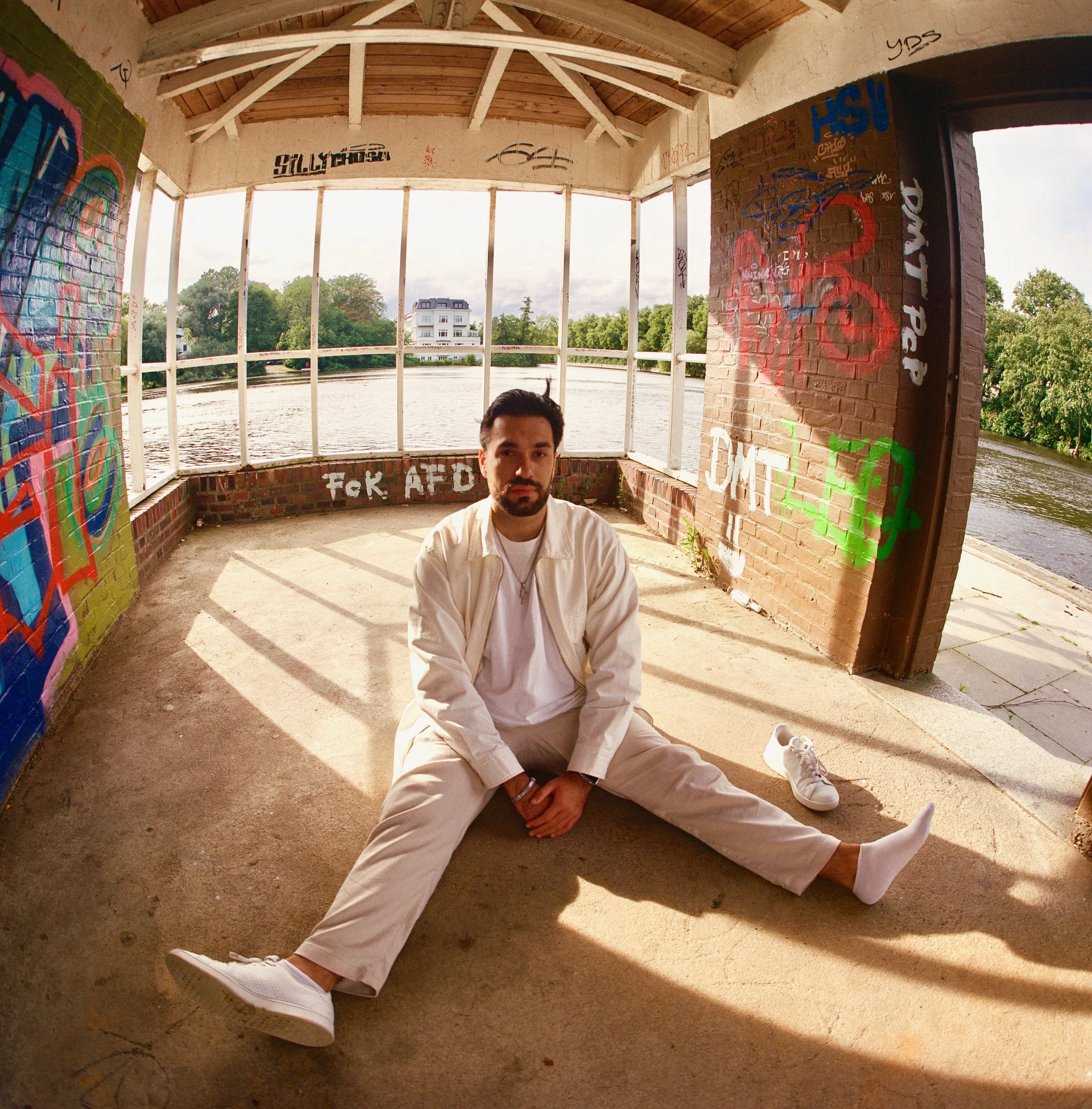Ein analoges Fisheye-Portrait eines sitzenden Mannes in Hamburg an der Alster.