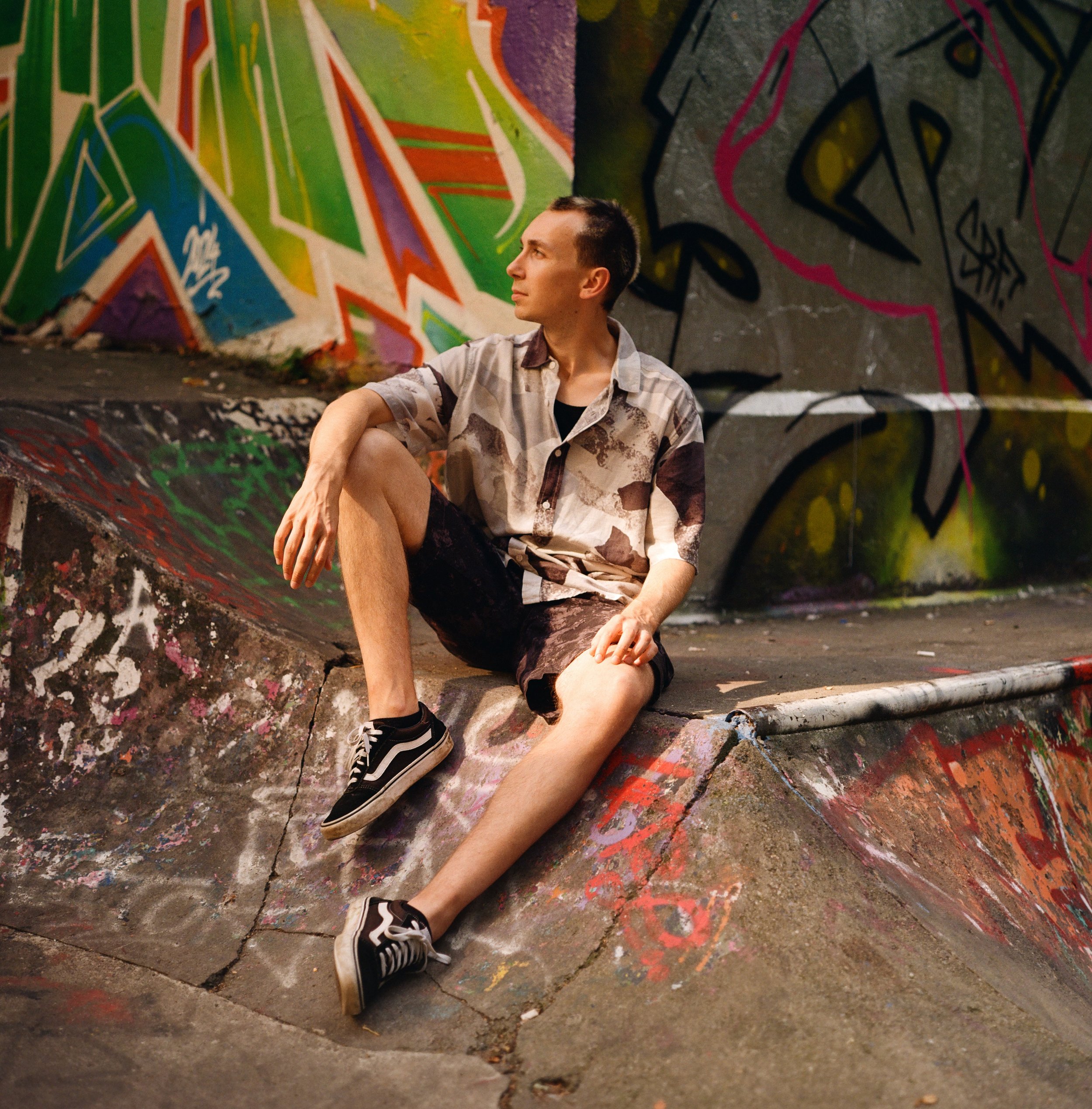 Analoges Bild eines Skaters, im Hintergrund sind viele bunte Graffiti zu sehen.