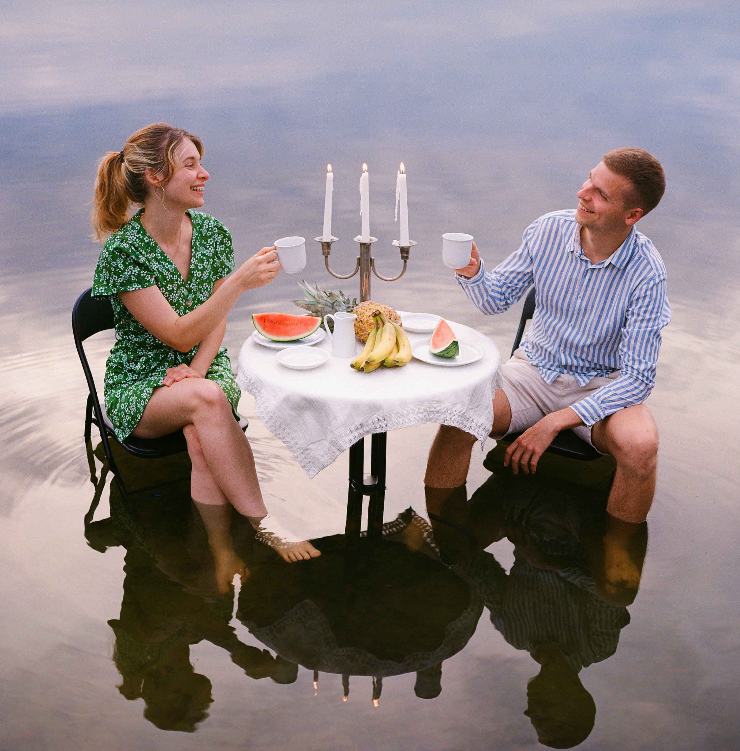 Eine Frau und ein Mann trinken in diesem analogen Foto zusammen Kaffee im See, sie sitzen an einem reich gedeckten Tisch mit Kandelaber.