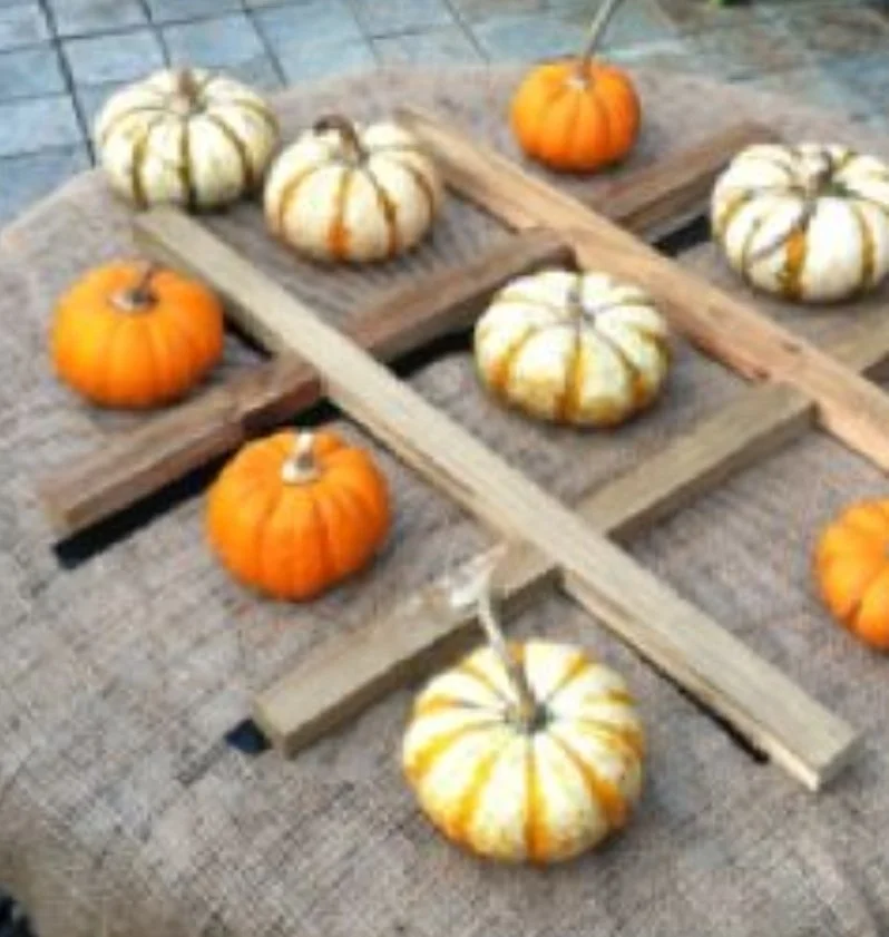 A display of various pumpkins, including white and orange ones, arranged on wooden planks on a table.