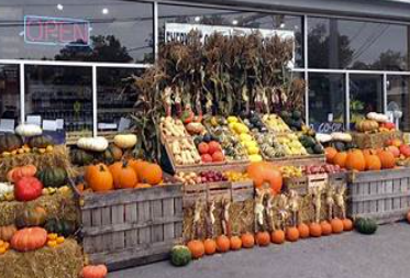 Fall display outside a store with pumpkins, gourds, and autumn decorations.