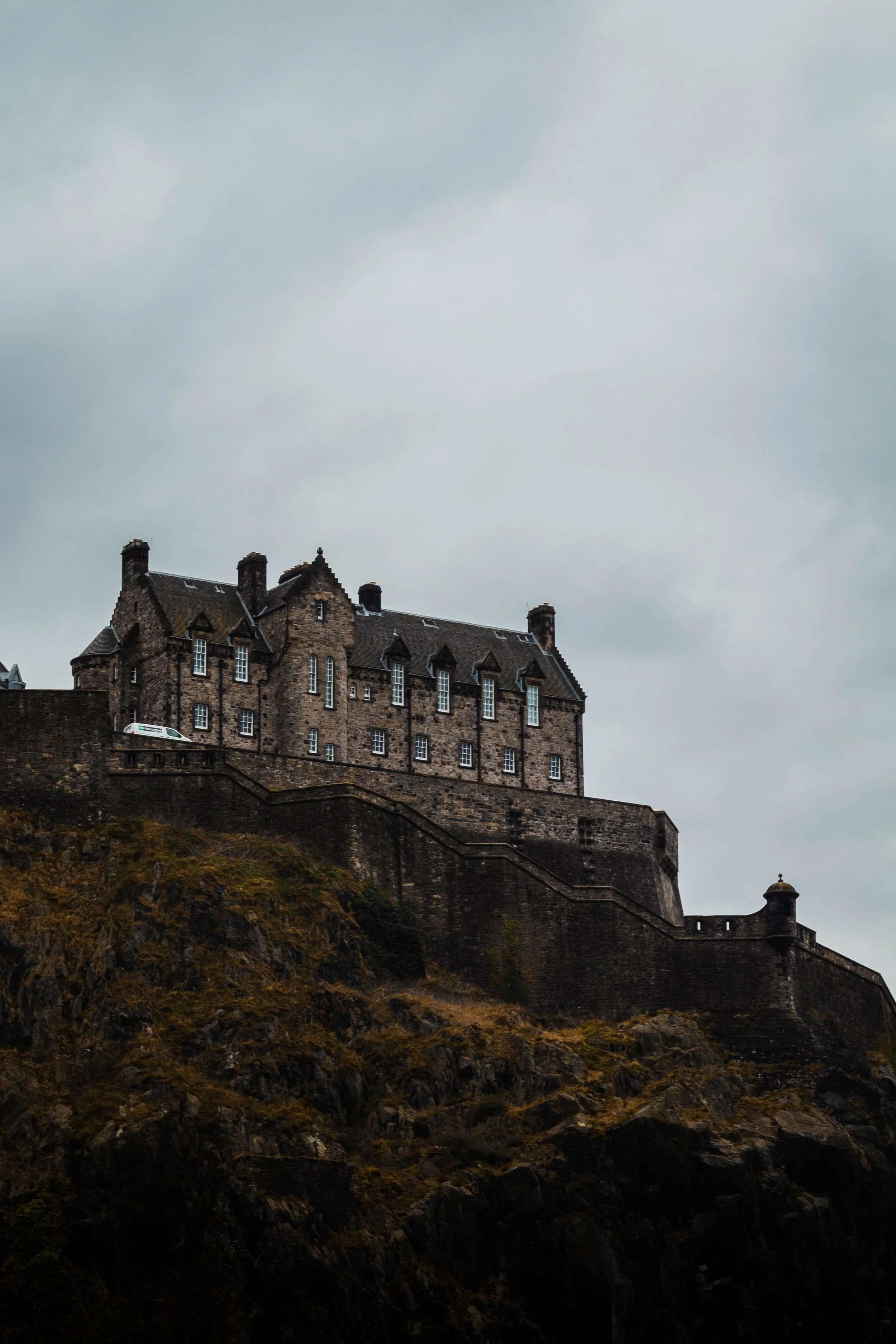 A large stone castle on a rocky hilltop under a cloudy sky.