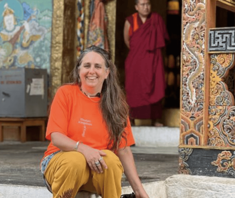 A smiling woman sitting on the steps of a Buddhist temple