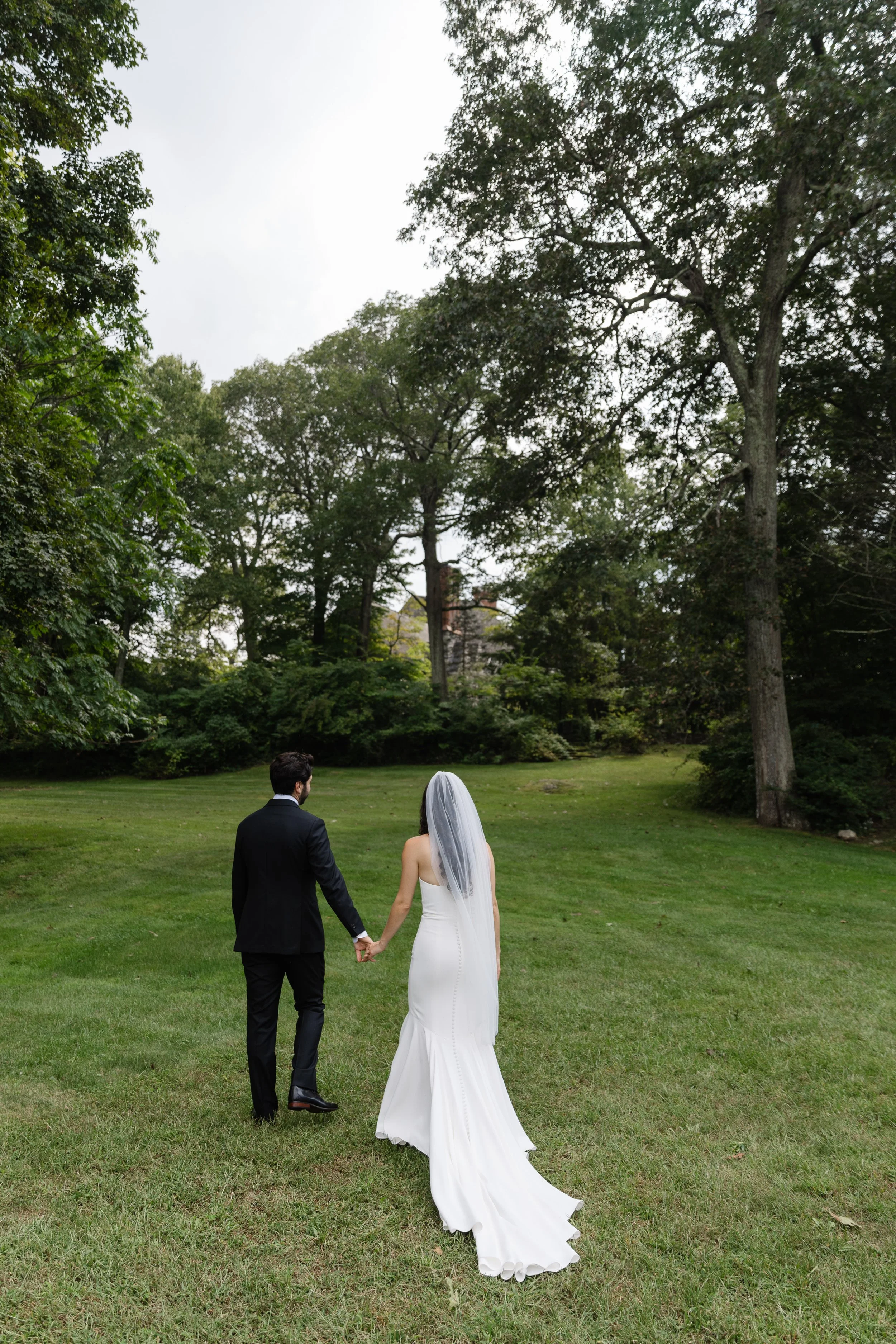 Bride and groom walking hand in hand across the lawn at a private estate wedding in Westchester County, Upstate New York, near New York City