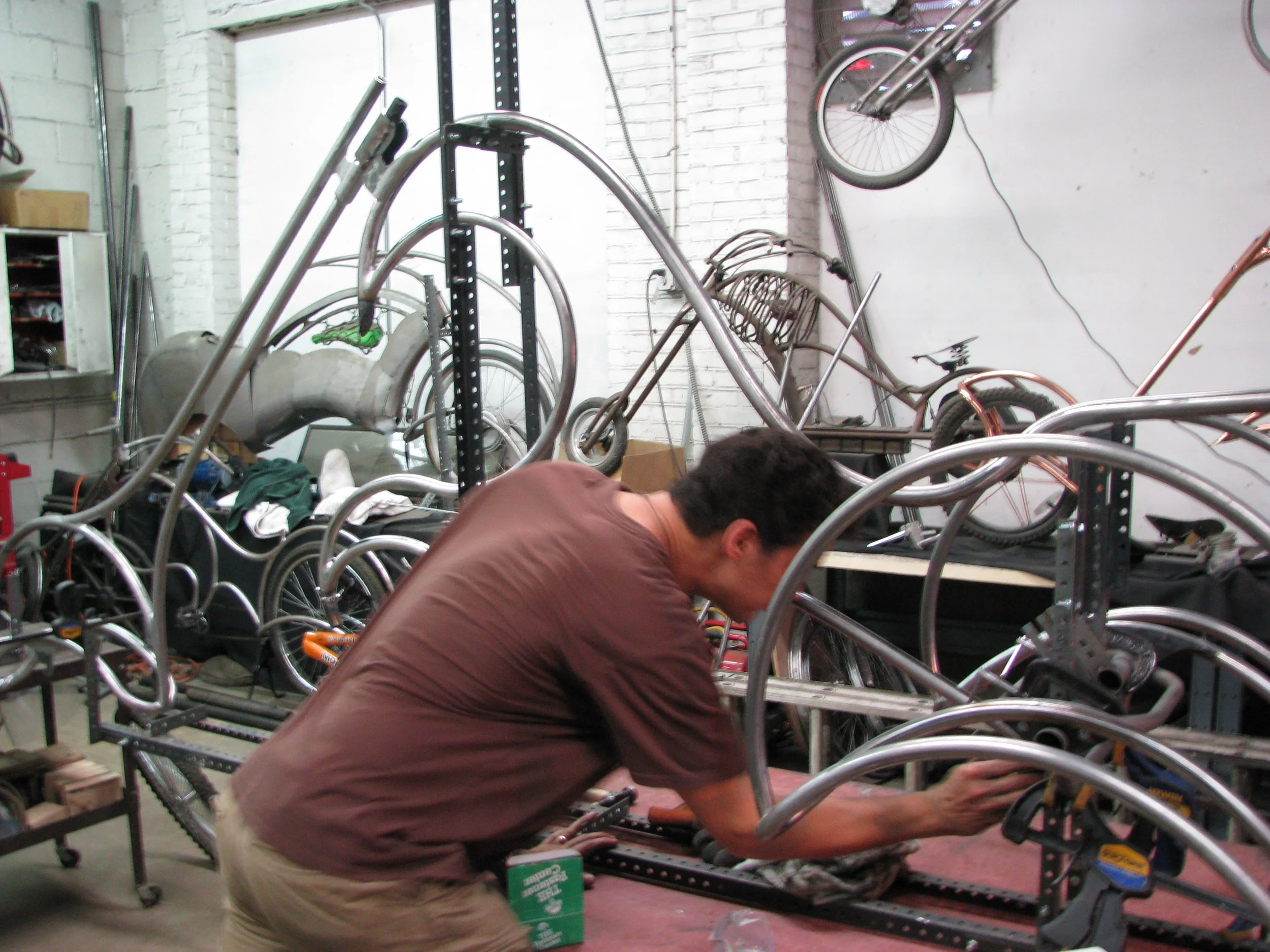 Josh building a metal bicycle frame in his studio, representing the creative residency at 20 Manor estate in New York
