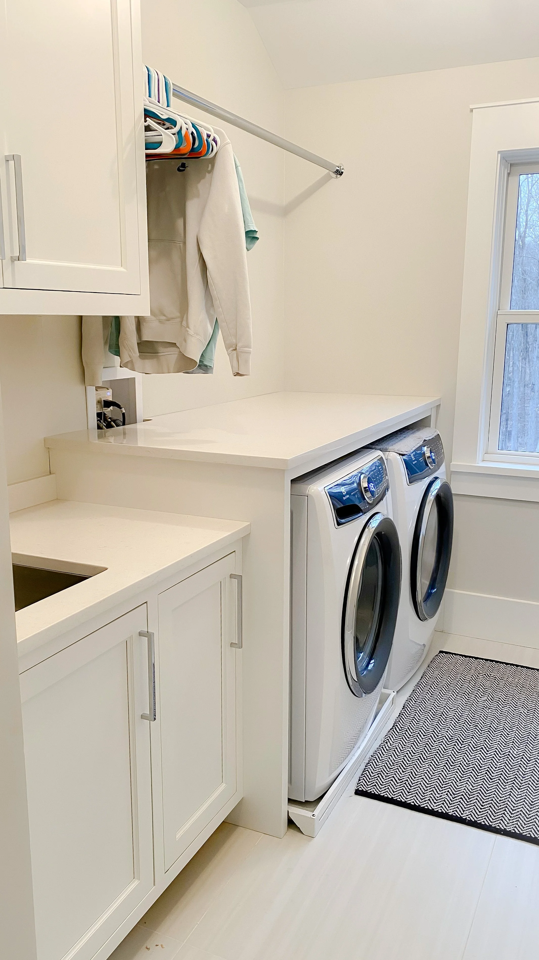 Functional white laundry room cabinets with sleek silver hardware, providing ample storage above a washer and dryer in a Connecticut home.