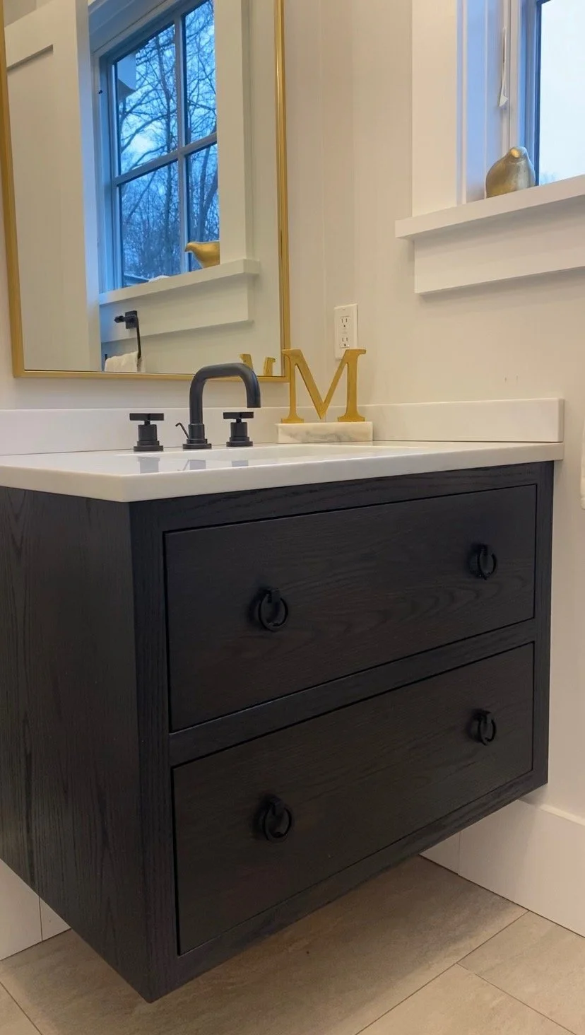 Custom black powder room vanity with elegant gold hardware and a white marble countertop in a Fairfield County modern rustic home.