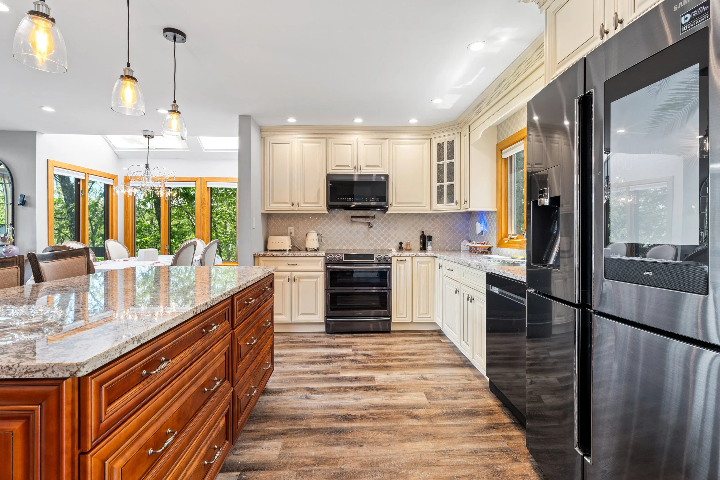 Kitchen with cream cabinets, black stainless steel appliances, and a wooden island with a marble countertop.