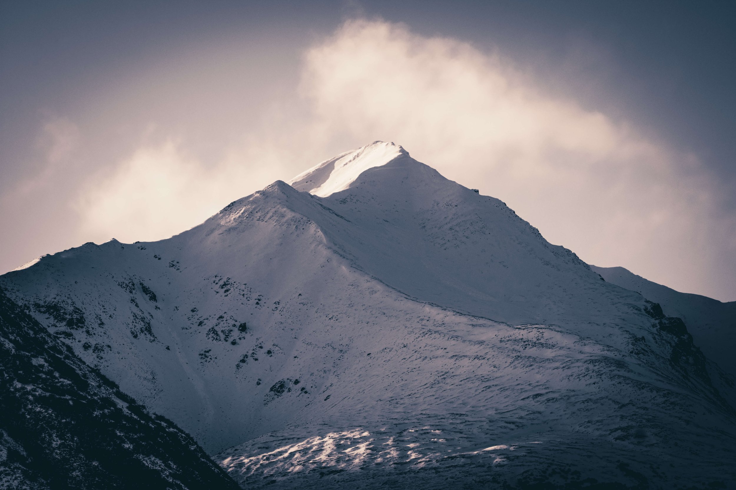 Soft morning light, photograph of snowcapped mountain peaks face, intimidating mountain range, clouds, Alaska, USA.