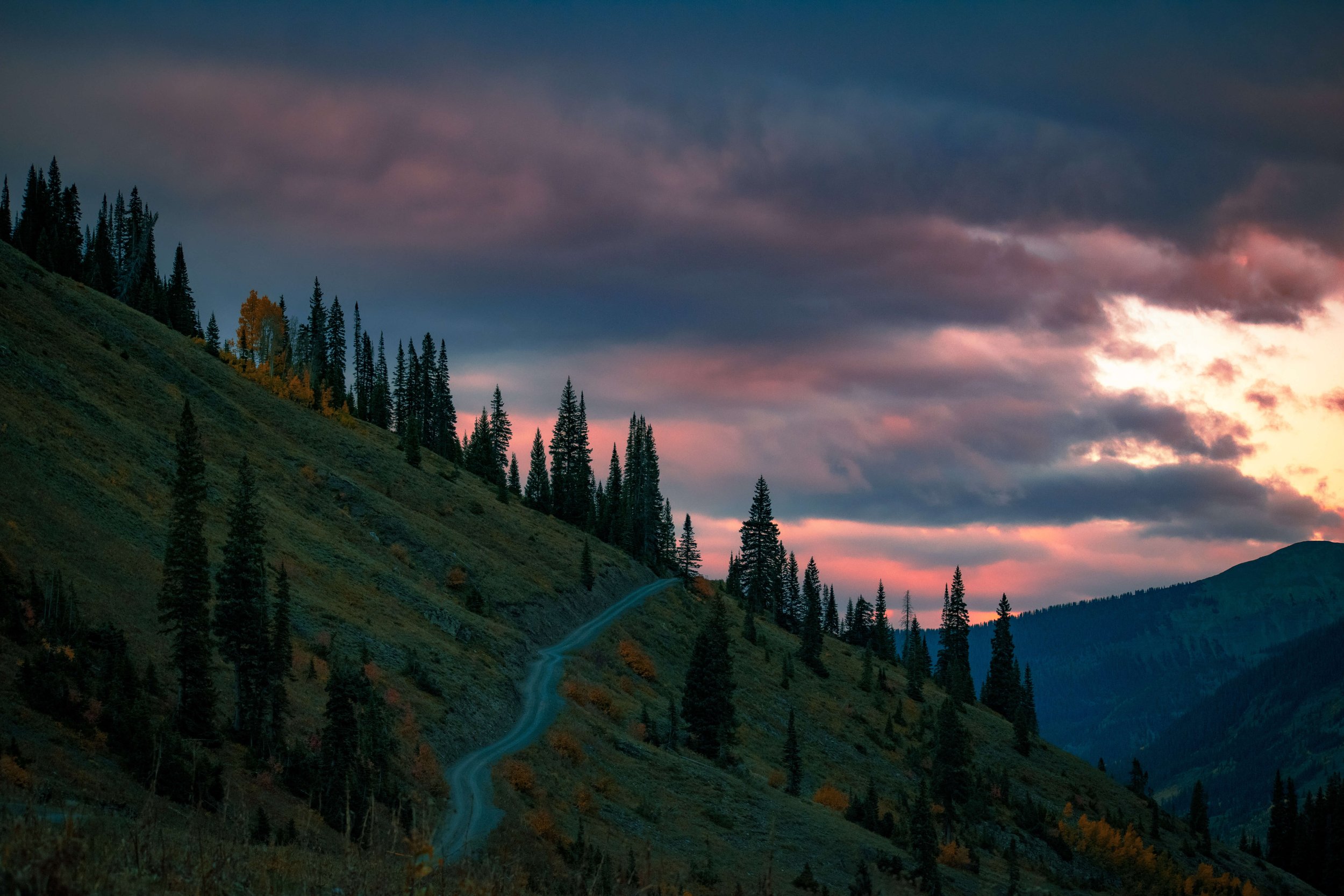 Schoefield Pass Road in Crested Butte at sunset, red stormy sunset skies, Camping, mountains of Colorado, stormy skies, mountain off road, dirt road, 4x4, pine trees, Colorado, USA, tent camping, remote wilderness, Rocky Mountains, Rockies, USA.