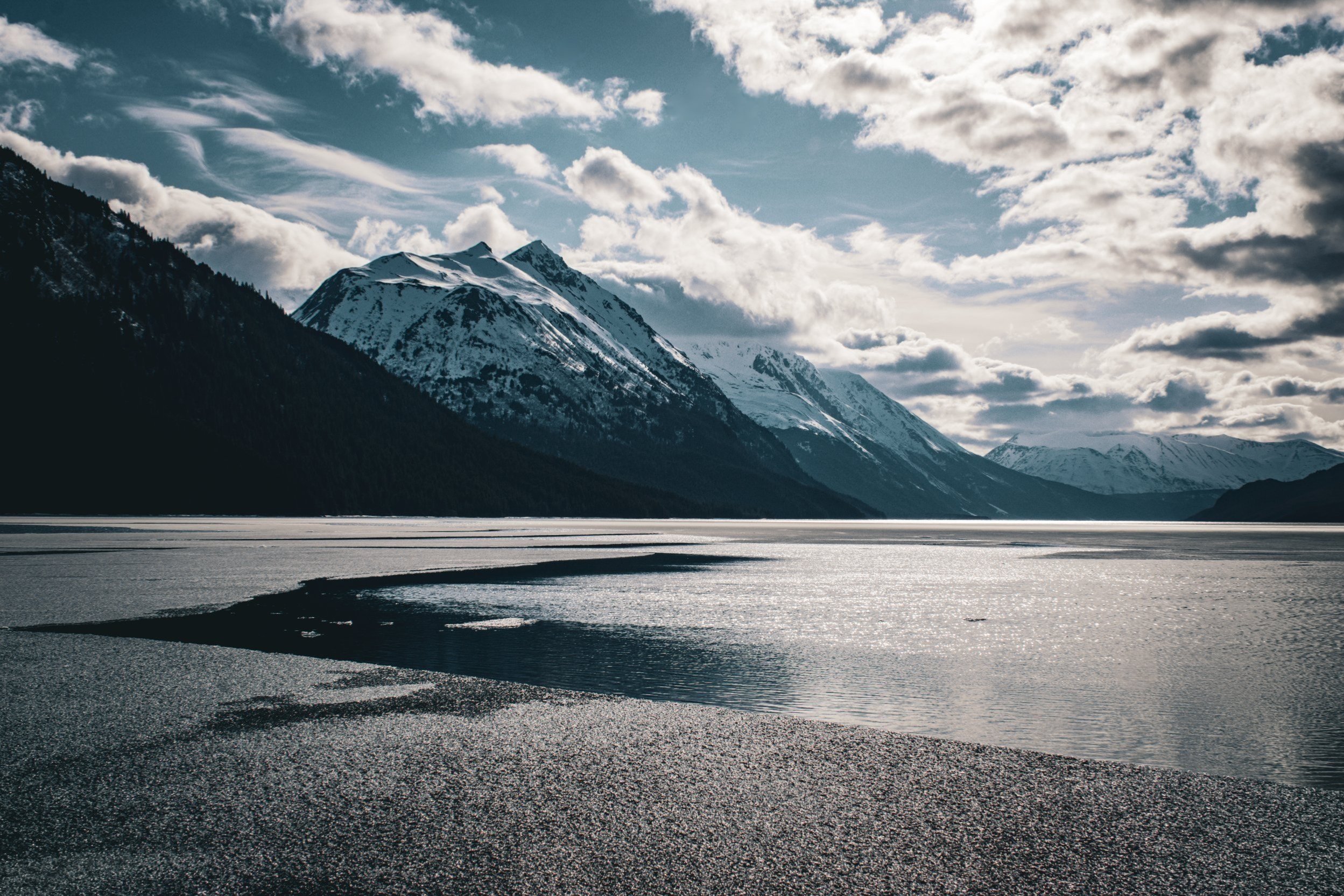 Seaward highway, a drone photograph of a remote Alaskan mountain range, snowcapped mountain peaks, mountain glaciers, frozen lake, ice, ice burgs, Alaska, USA, remote wilderness, clouds, blue sky.
