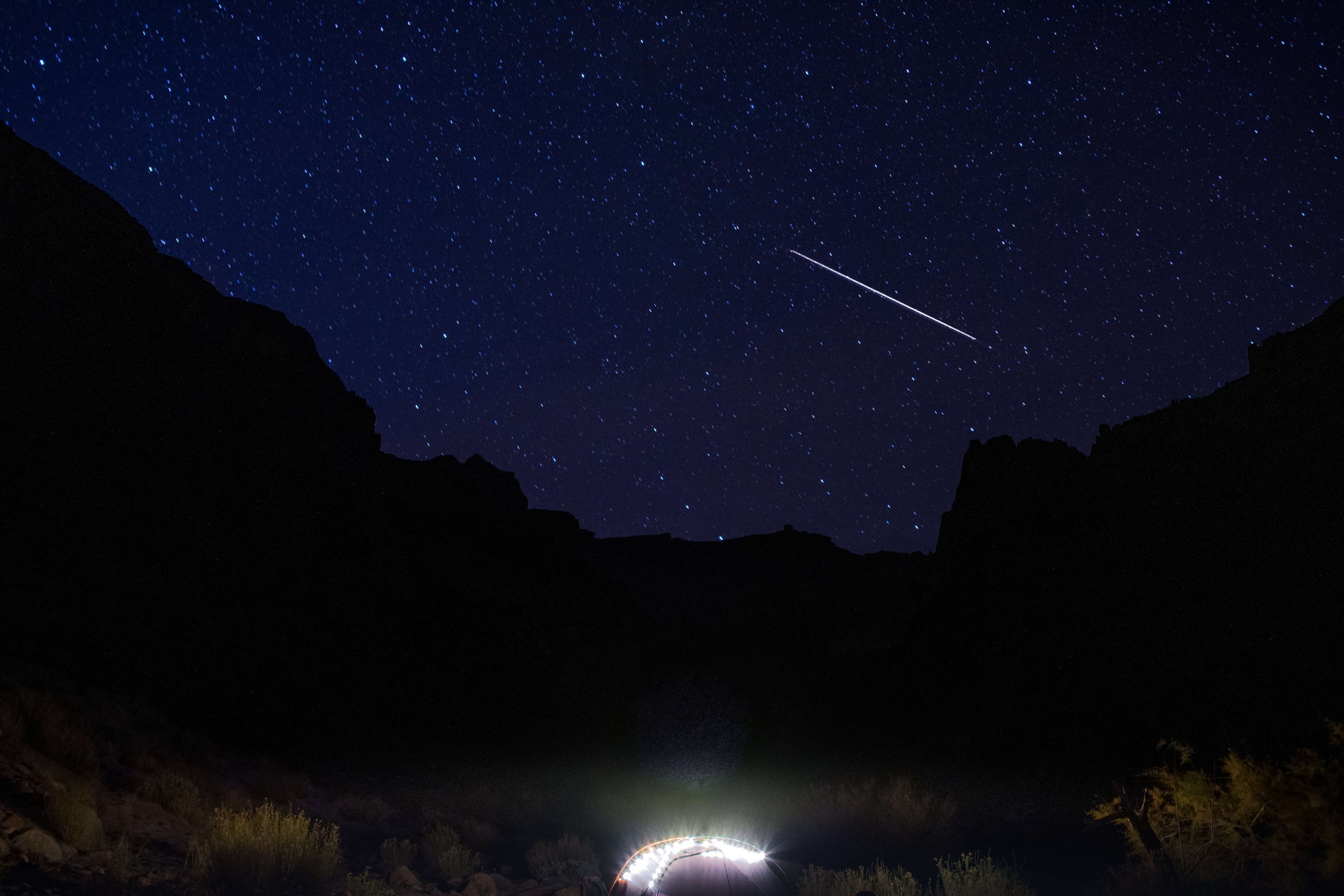 View of a shooting star and the Milky Way rising from a camp site on the shores of Hermit Rapids on the Colorado River, Grand Canyon National Park, Arizona, USA, south rim, astrophotography, river, backpacking, hiking, tent, starry night, desert, nat