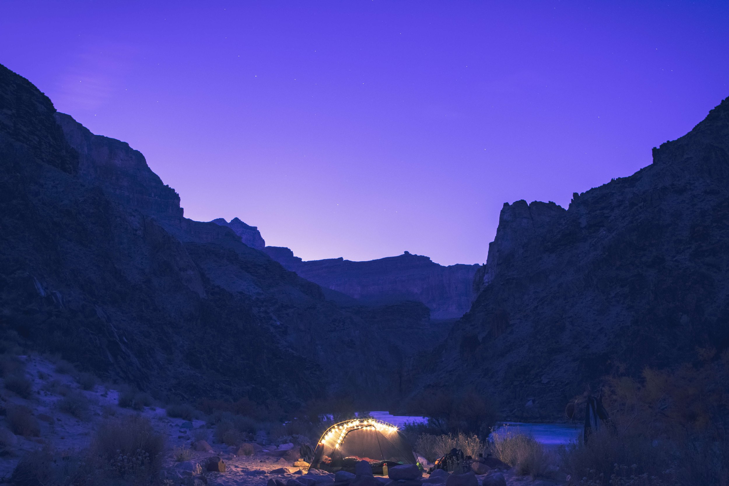 Purple evening sky, twilight, stars rising over a camp site on the shores of Hermit Rapids on the Colorado River, Grand Canyon National Park, Arizona, USA, south rim, river, twinkle lights, backpacking, hiking, tent, REI, evening glow, starry night,