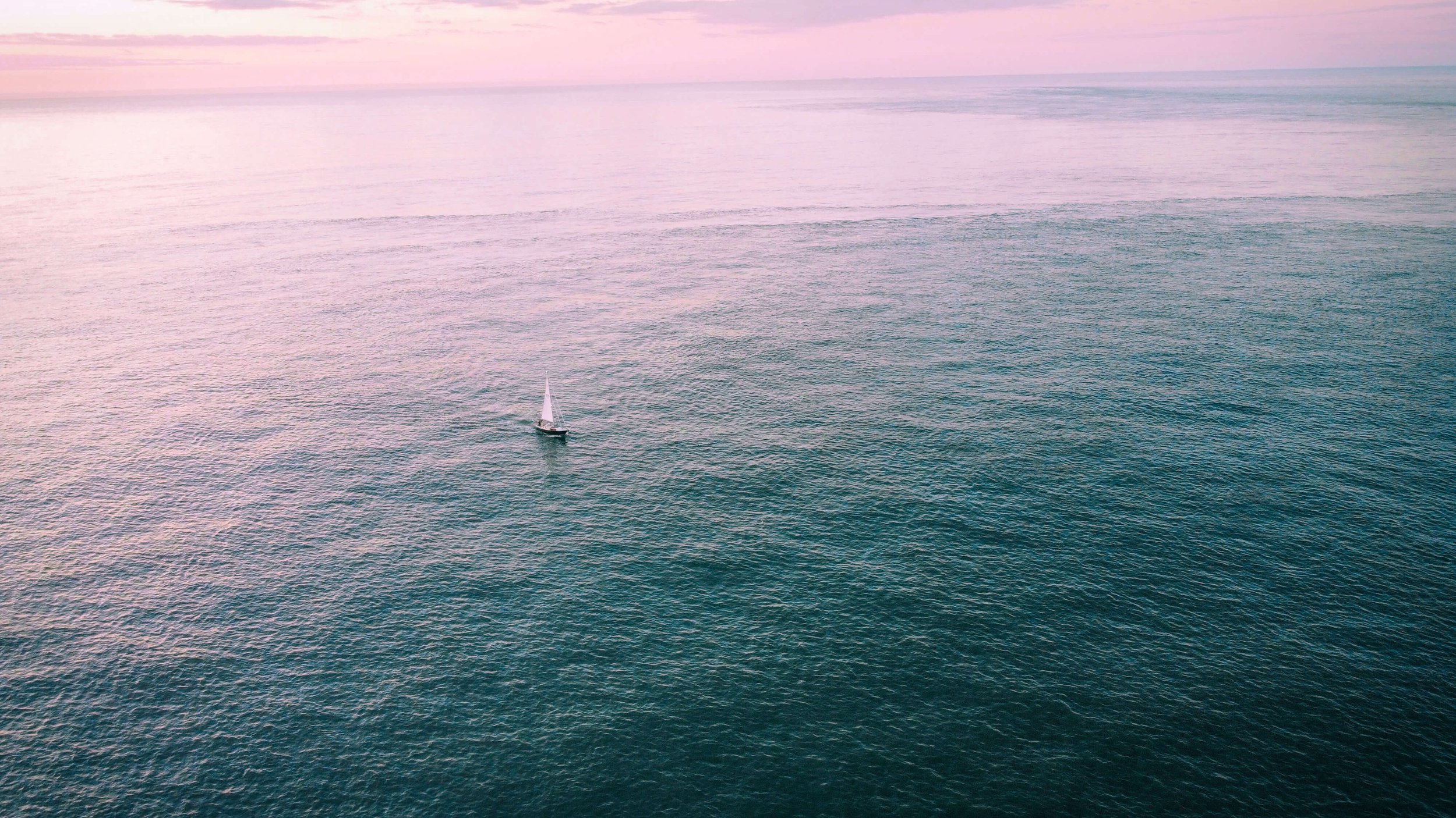 a lone sailboat on the Atlantic Ocean, Cape May New Jersey, USA, Cape May Point, pink and blue sky, sunrise, morning, drone photography, calm sea, summer, beach, Jersey Shore.