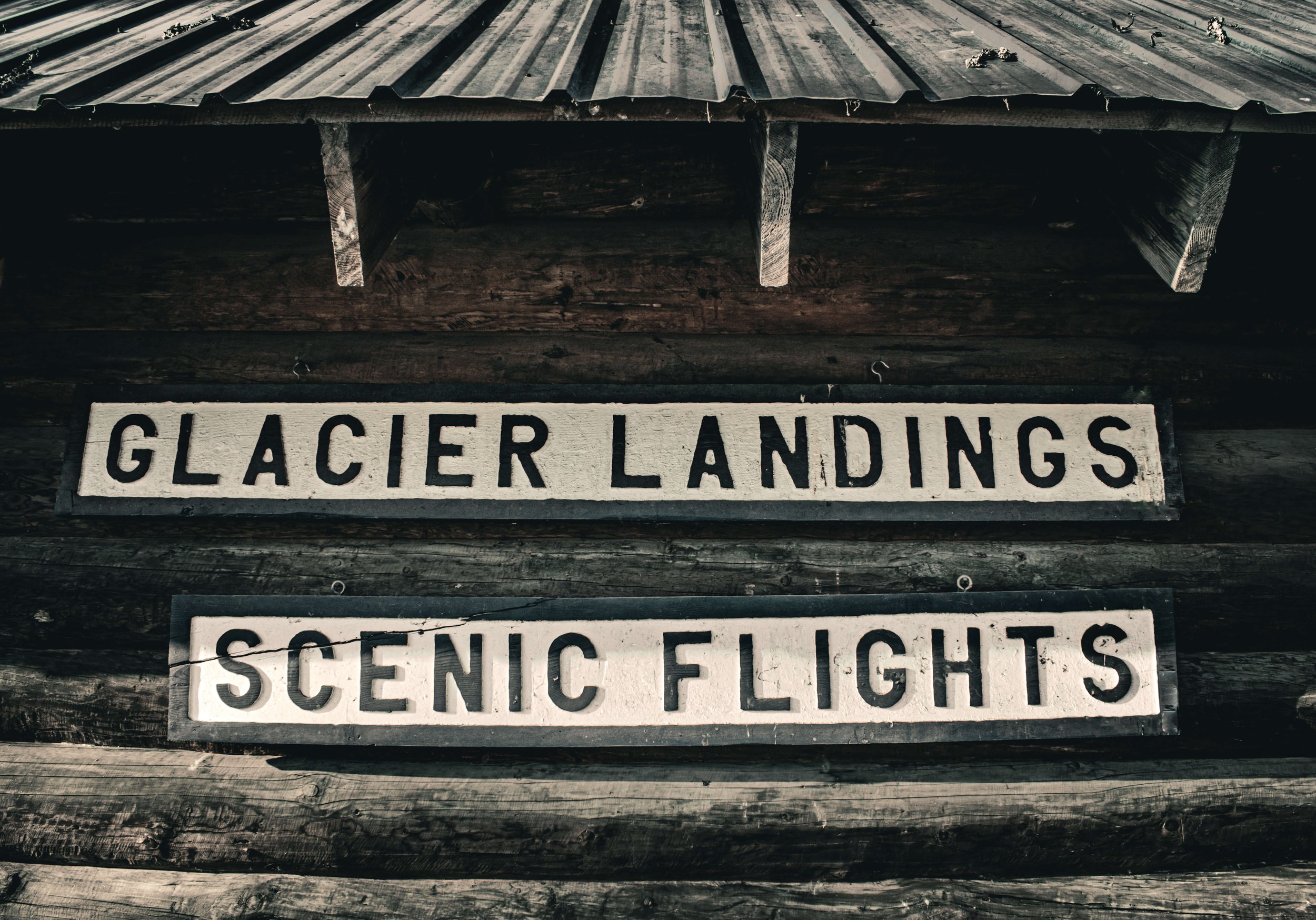 Glacier landings, scenic flights, vintage rustic signs, Alaska air tours, log cabin, Alaska, USA.