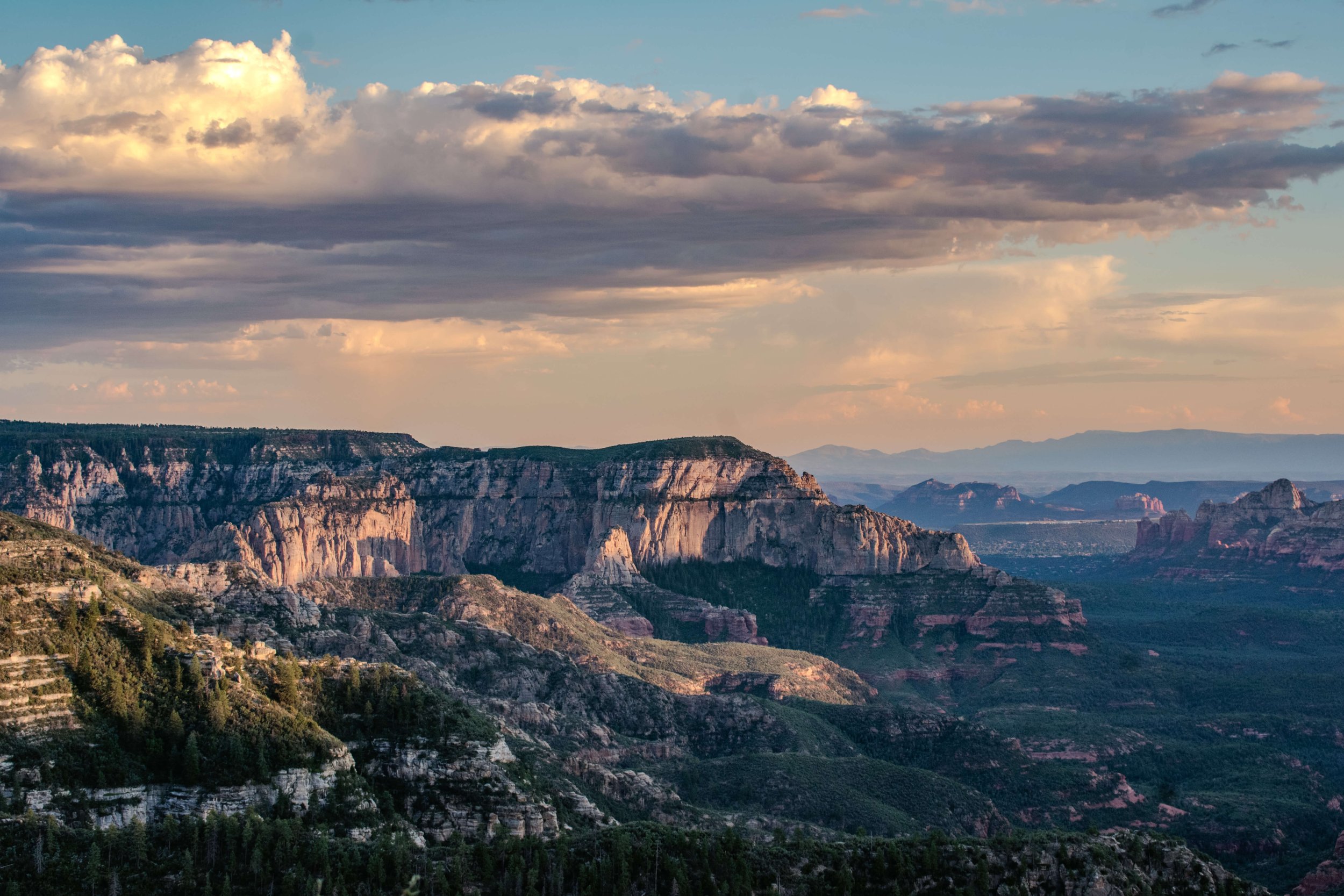 Sunset light rays illuminate a high desert forested canyon in Northern Arizona, Sedona, Arizona, USA, red rocks, Edge of the World, camping, hiking, desert, cliff edge, sunrise, golden hour, American Southwest.
