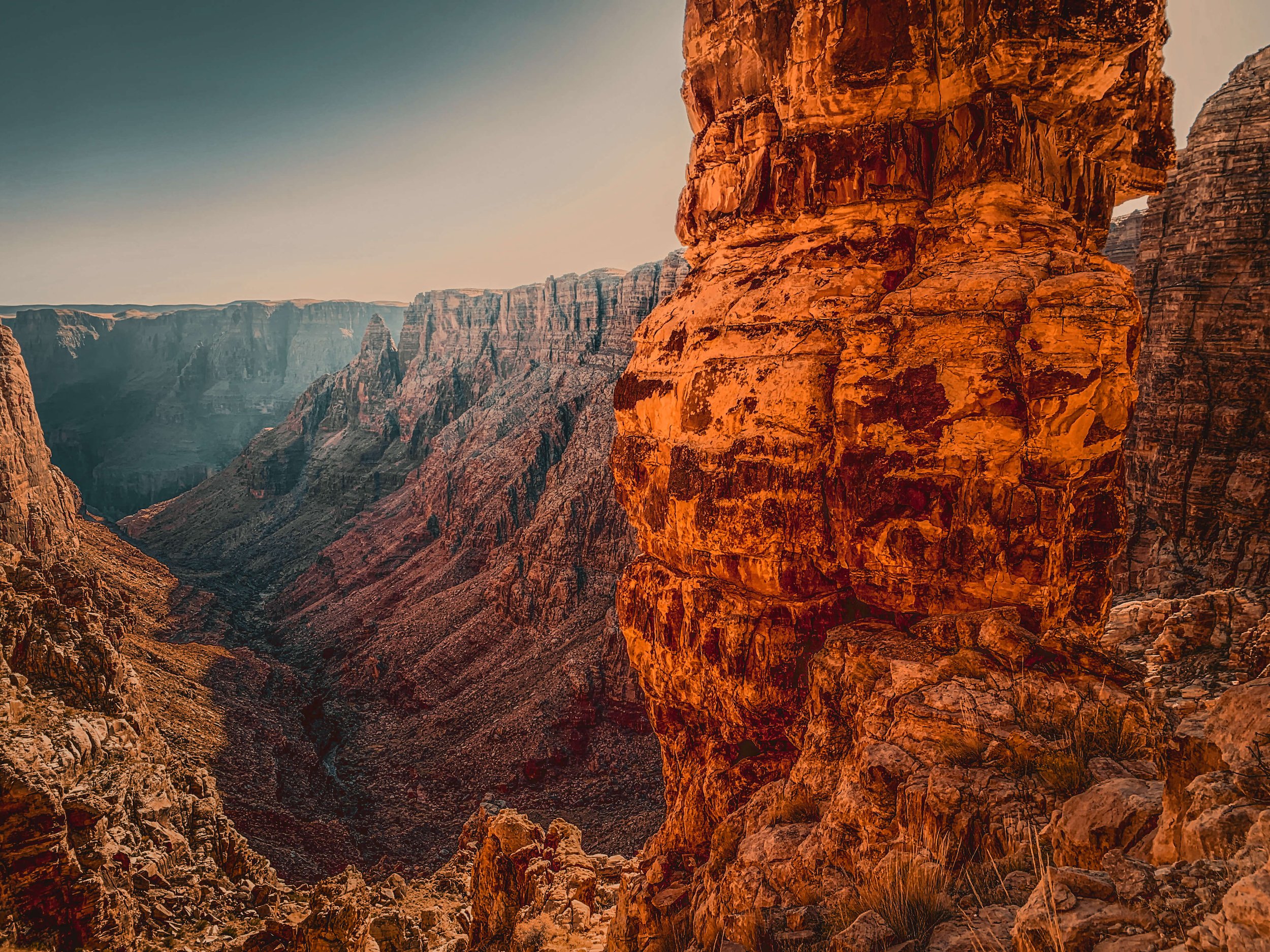 Canyon landscape with steep rocky cliffs in warm sunlight, Sunset golden hour, rim overlook, lookout, Grand Canyon National Park, Arizona, USA, natural wonders of the world, hiking, cliff edge, northern Arizona, Colorado River, American southwest.