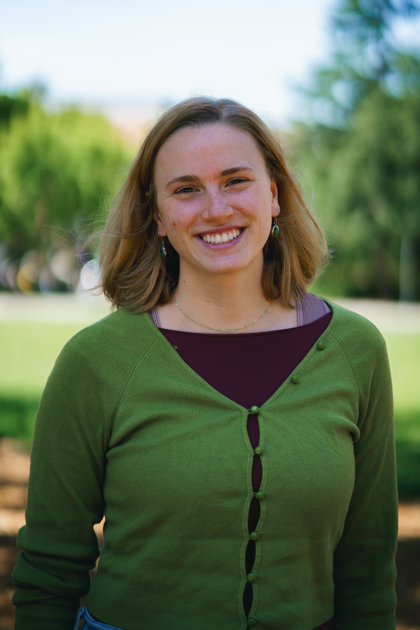 Laina Hall, graduate student, standing in front of a green field with green hills in the background