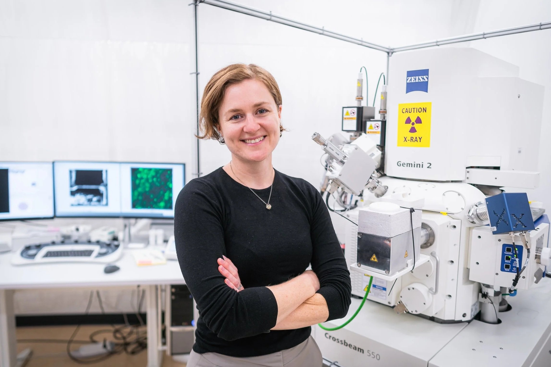 Bronwyn Lucas, Principle Investigator, standing in front of a focused ion beam scanning electron microscope