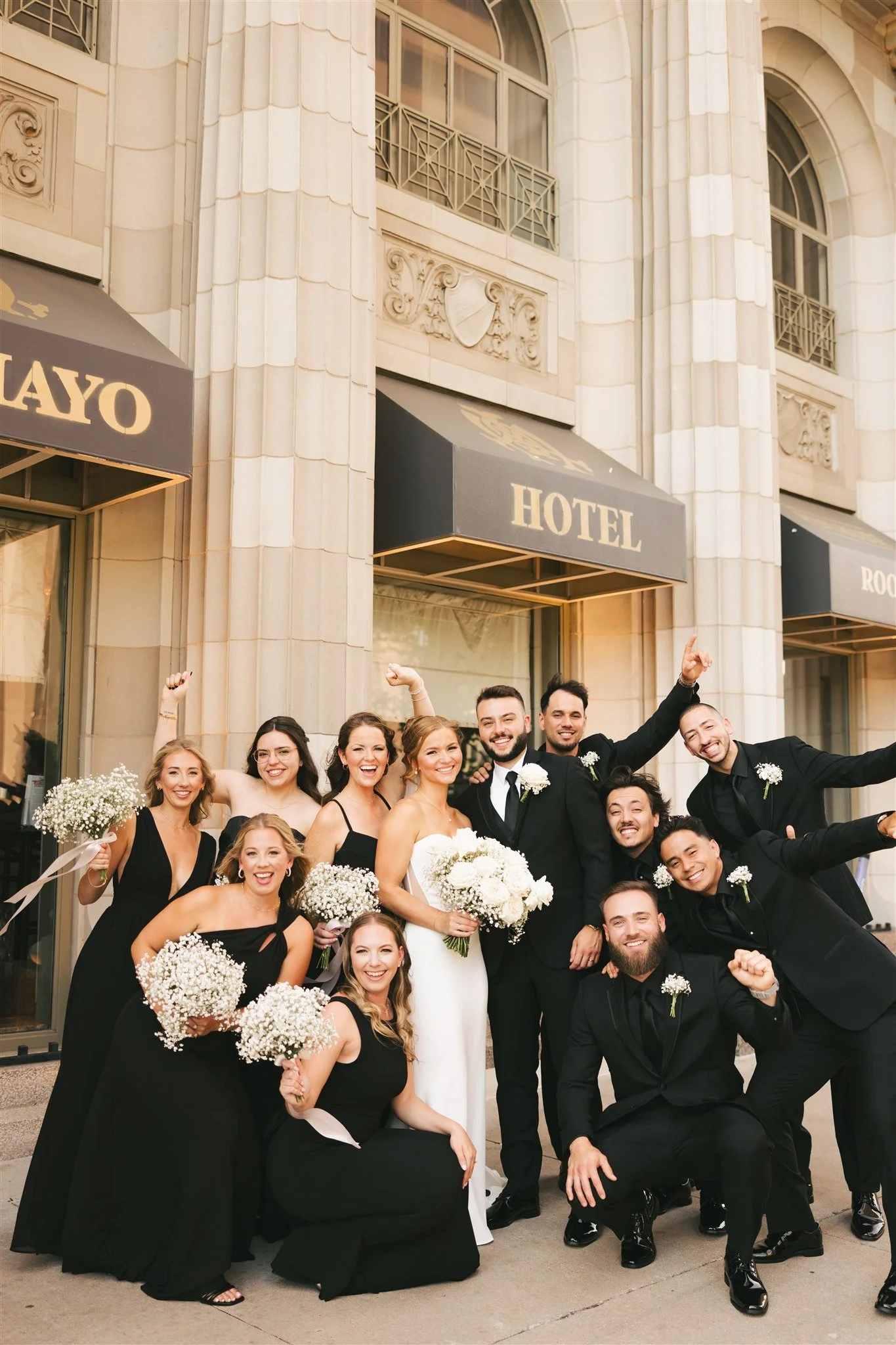 wedding party standing outside of hotel venue celebrating the couple with portraits