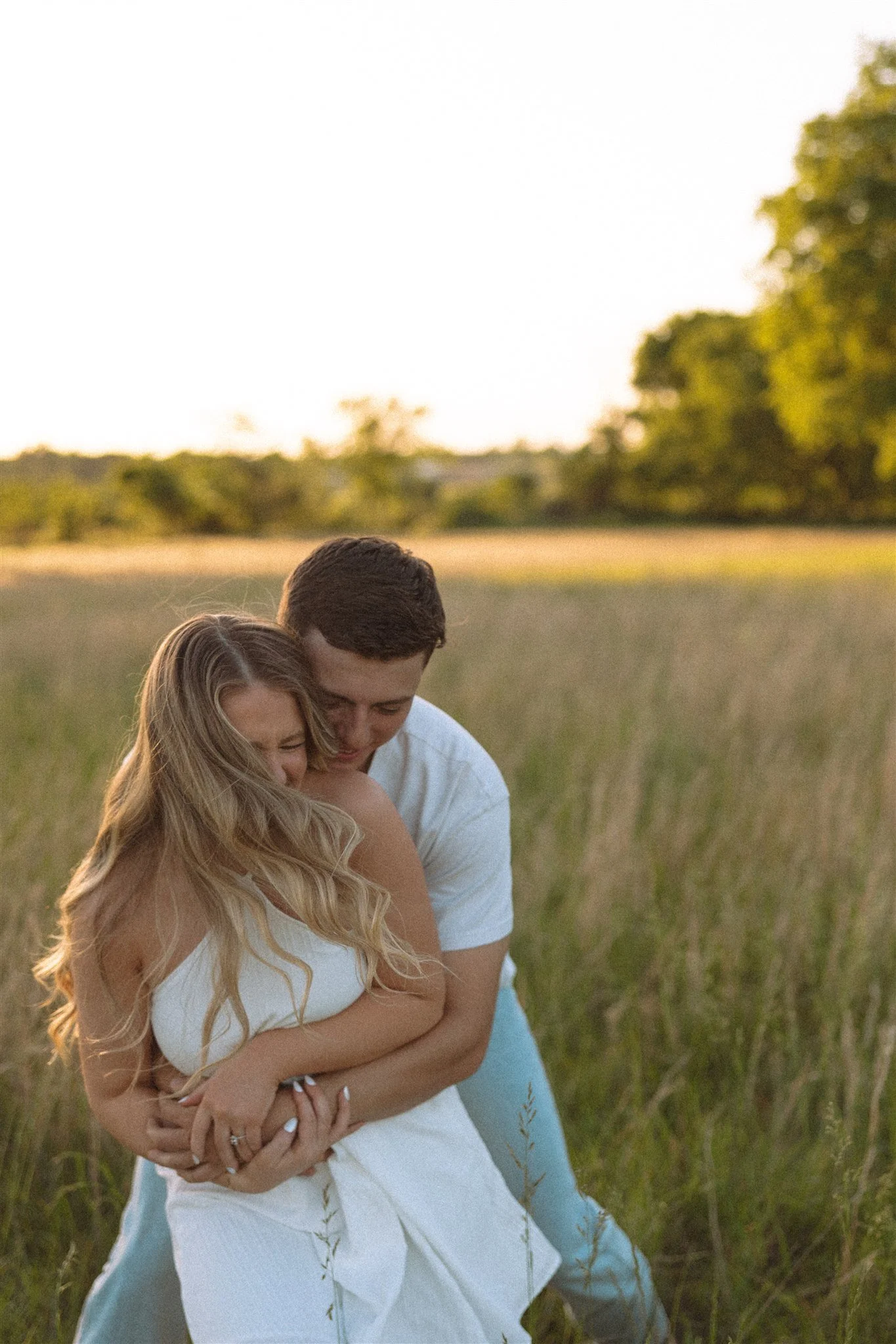 a couple sharing a playful moment running in a field as the man catches the woman
