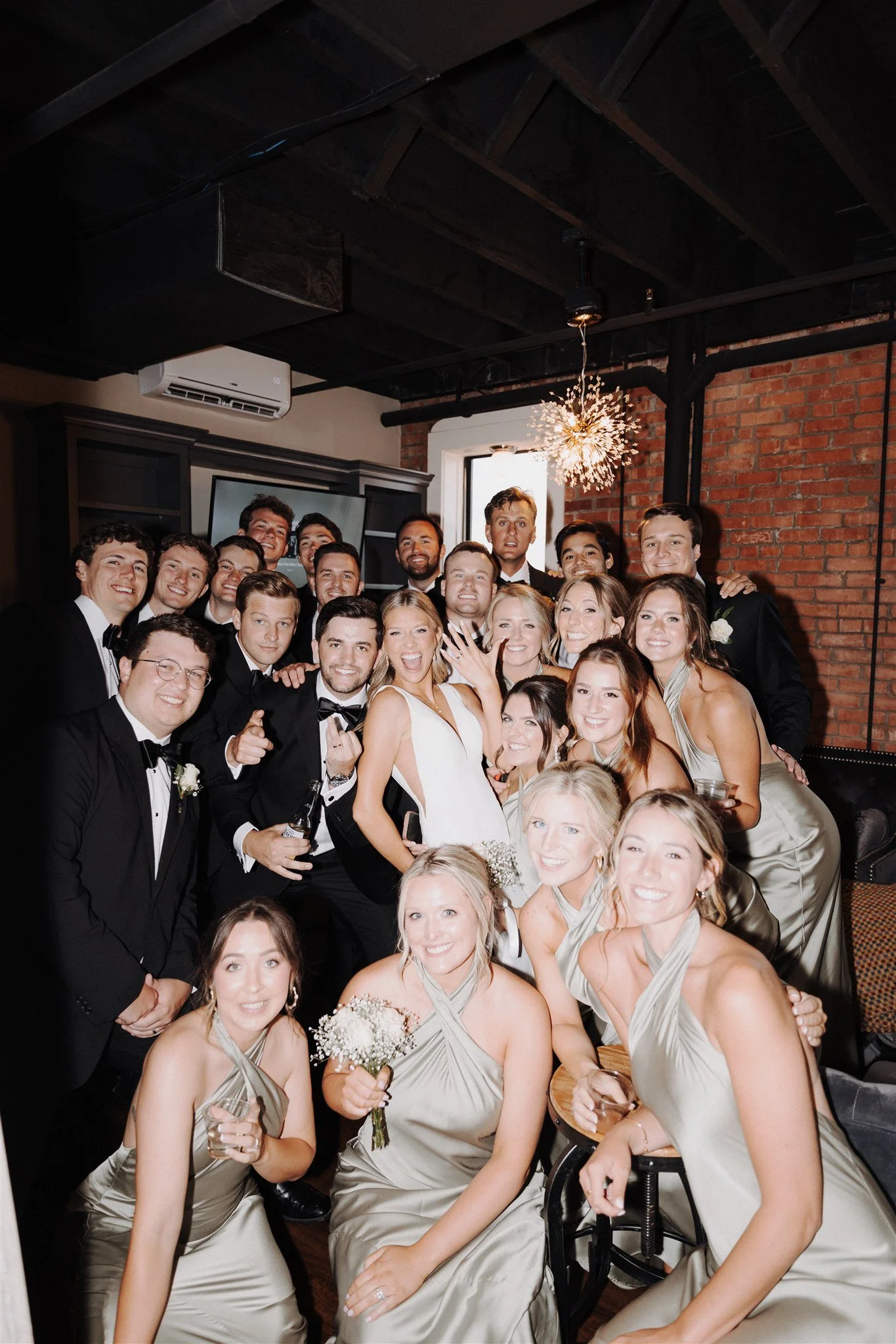 wedding party photos gathered around bride and groom with bridesmaids wearing sage green dresses and men in tuxedos