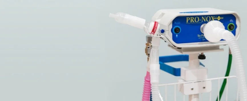 Medical ventilator machine with attached breathing tubes in a hospital setting.