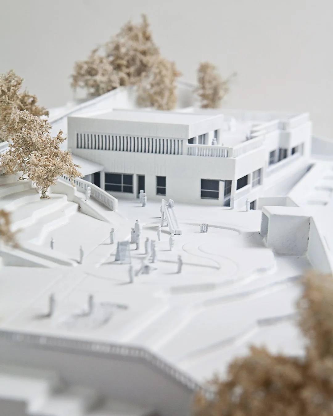Architectural model of a modern, white building with trees and pathways.
