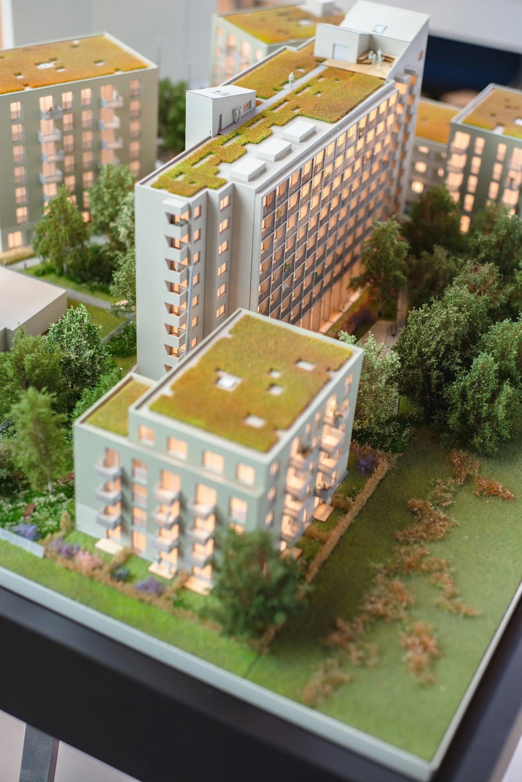 Architectural scale model of a modern residential building complex with landscaped green spaces and trees.