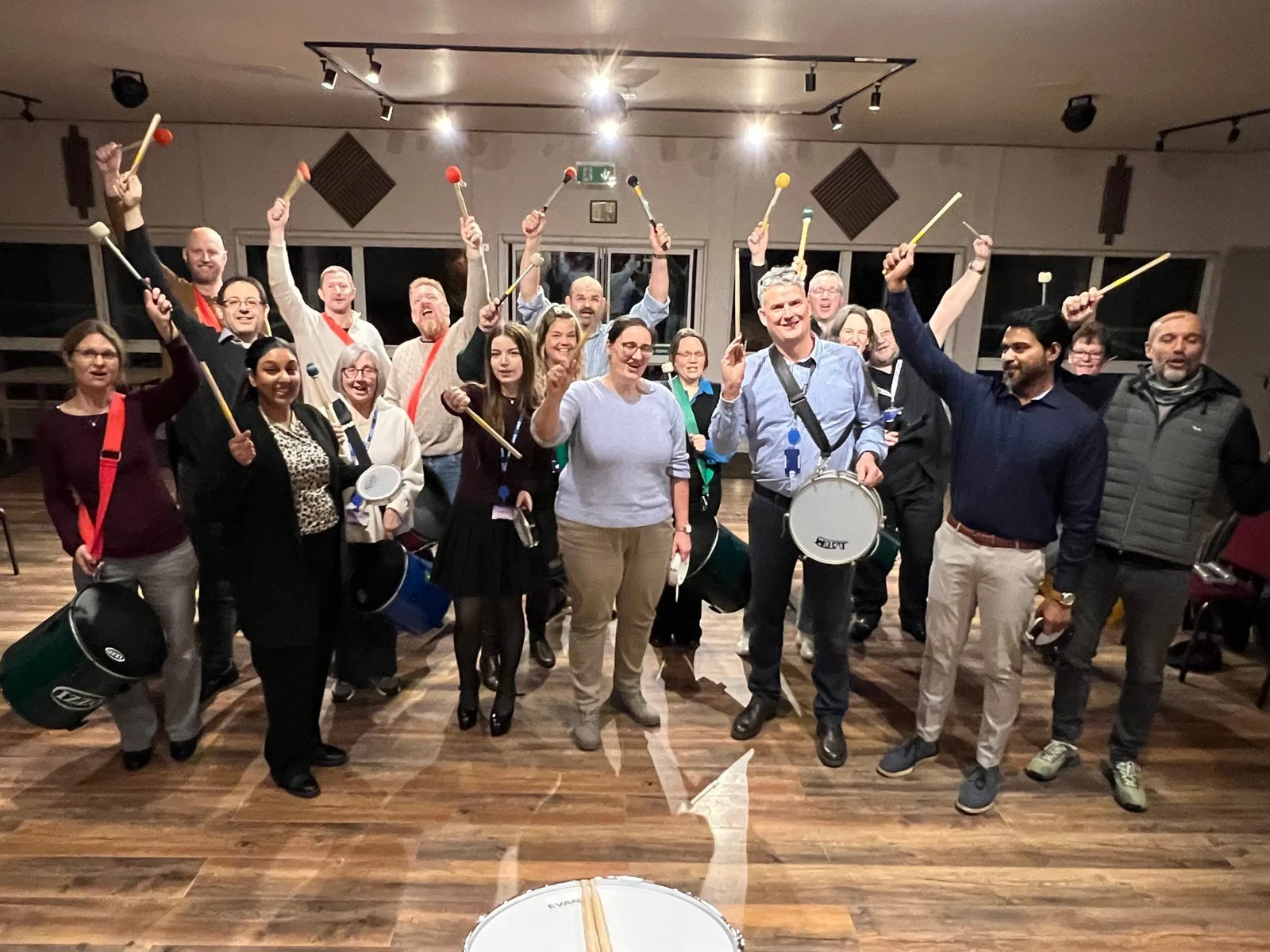 Corporate team cheering with drumsticks raised after their samba drumming finale