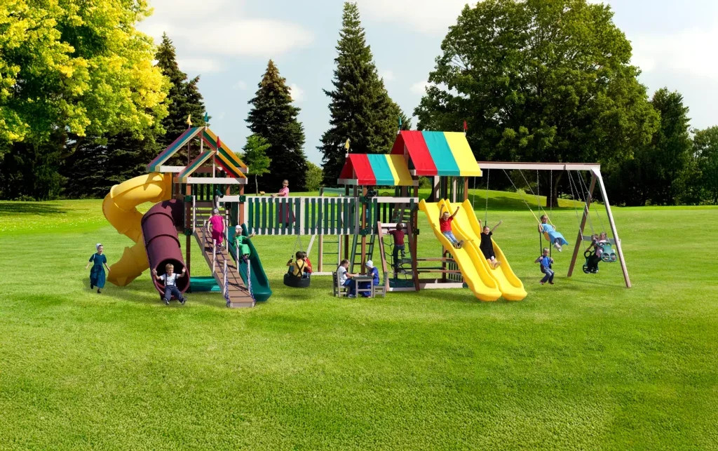 Colorful playground with slides, swings, and children playing on a grassy field surrounded by trees.