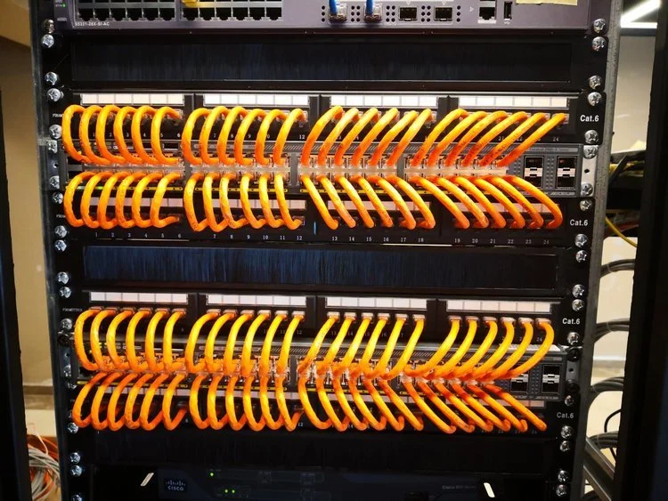 Server rack with neatly organized yellow Cat6 Ethernet cables connected to network switches.
