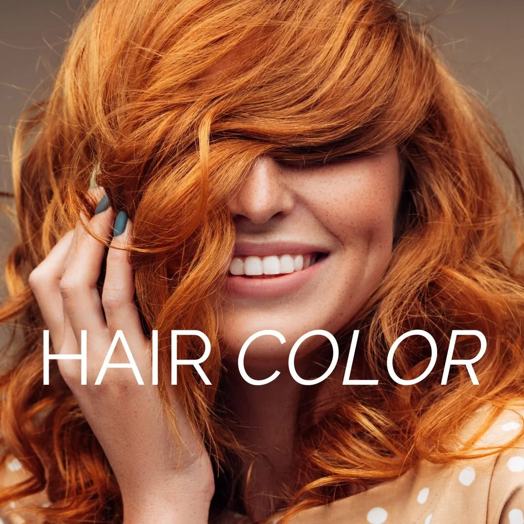 Close-up of a woman with long, wavy red hair smiling and touching her hair with her hand, with the words 'HAIR COLOR' overlaid.