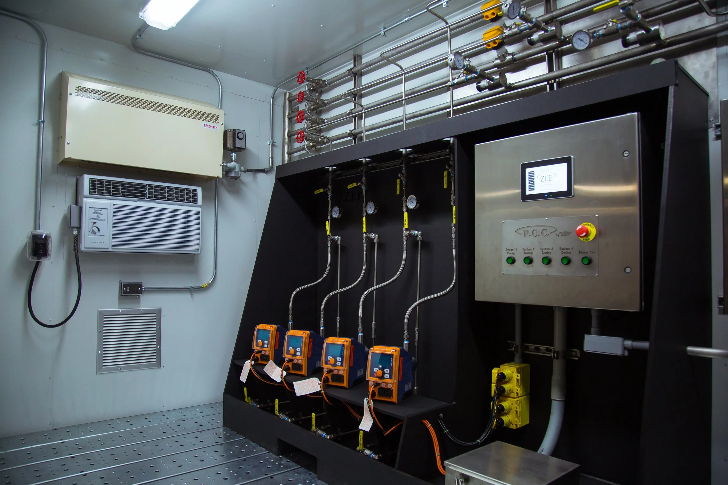 Industrial control room with gauges, pipes, sensors, and electrical panels.