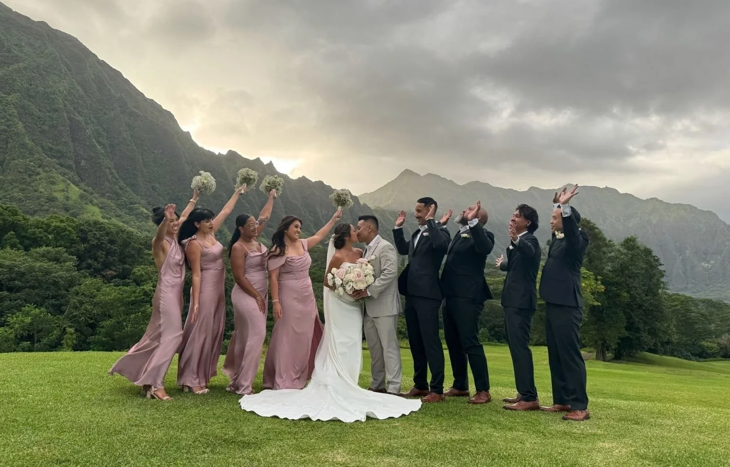Bridal party with bridesmaids and groomsmen celebrate outdoor Hawaii wedding. Koʻolau mountains garden photo inspiration for modern destination ceremonies.