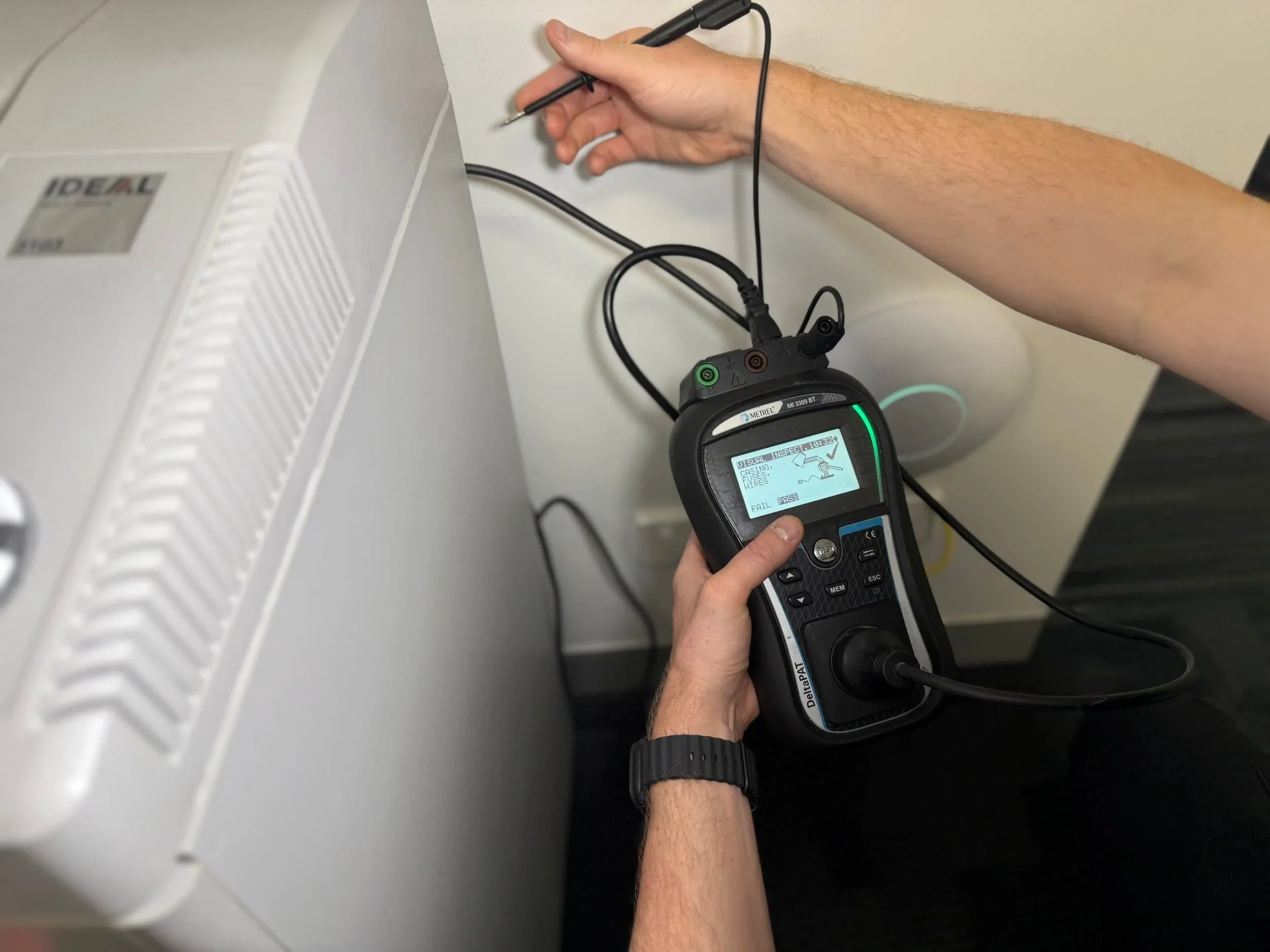 Technician using a portable appliance tester to inspect electrical equipment