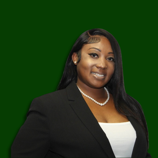 Professional woman with long black hair, wearing a black blazer, white top, pearl necklace, and earrings, smiling against a green background.