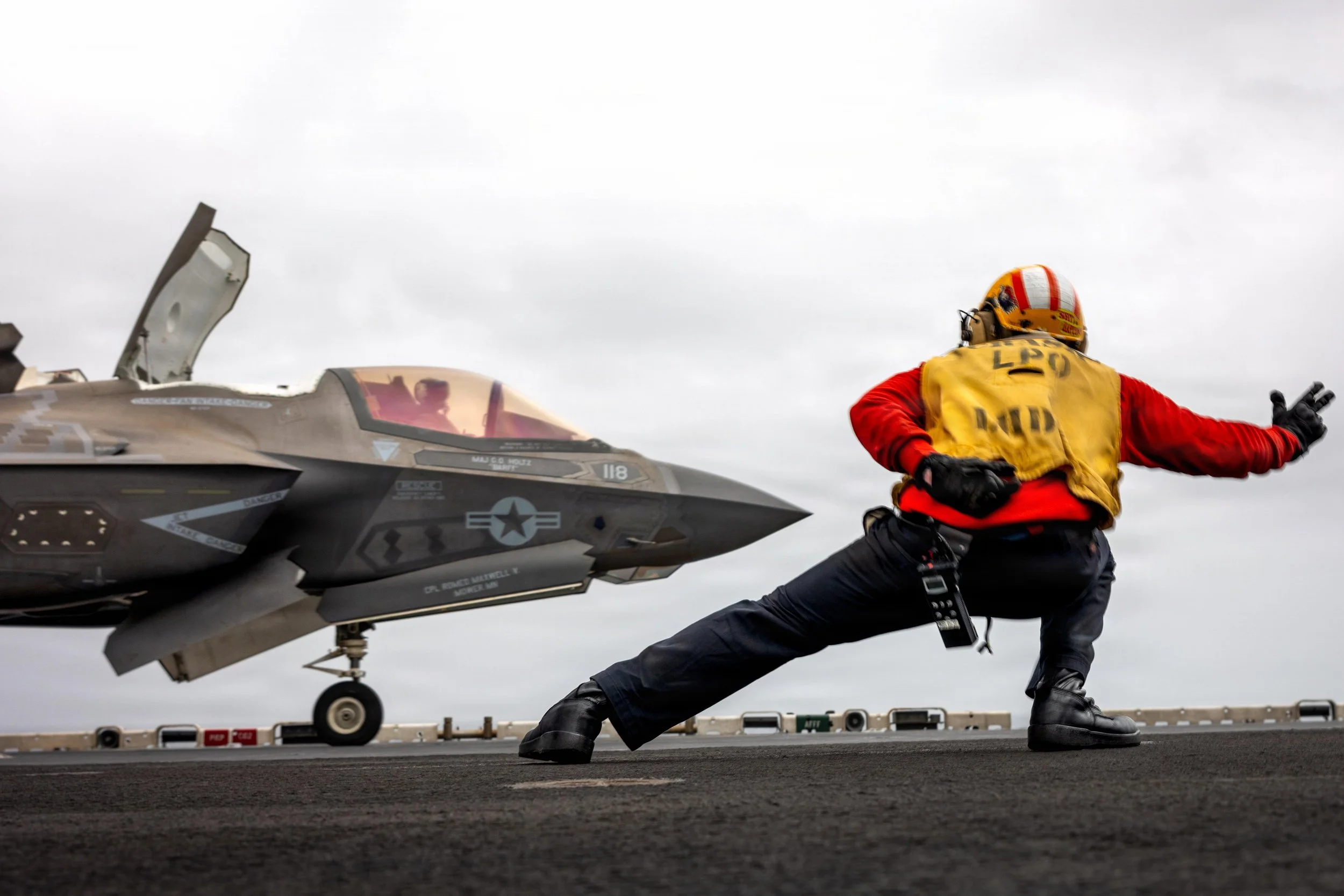 A sailor assigned to the amphibious assault ship USS Boxer signals a Marine Corps F-35B Lighting II to take off during flight operations in the U.S. Central Command area of responsibility, July 17, 2026.